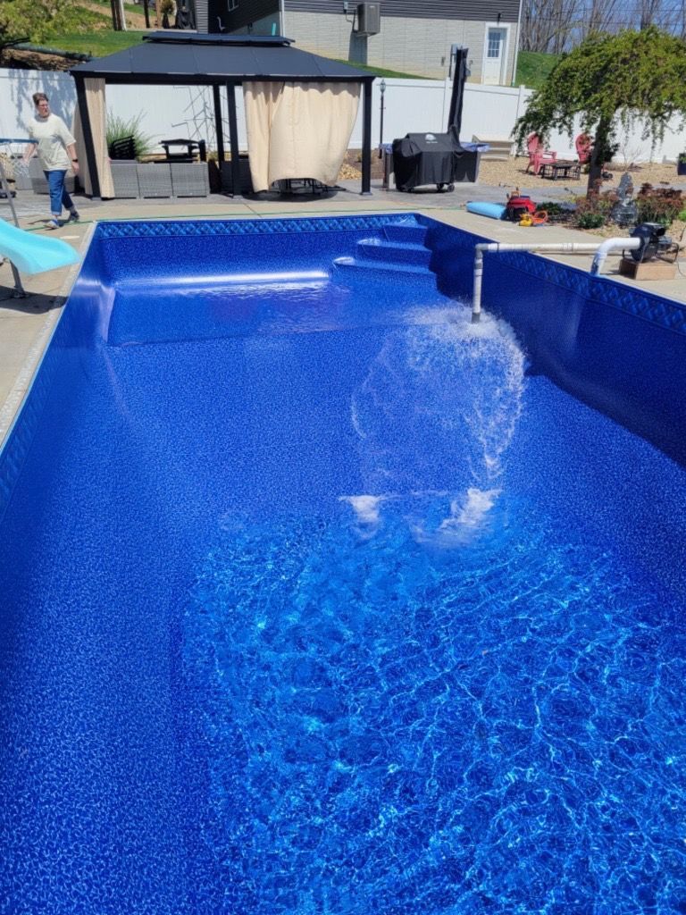 Blue swimming pool with water splashing into it in a sunny backyard area