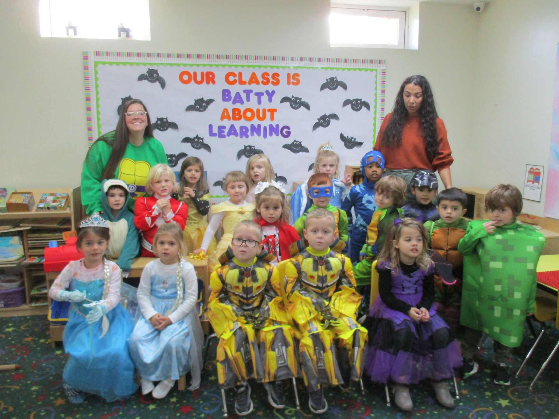 A group of children are posing for a picture in front of a sign that says our class is patty about learning.