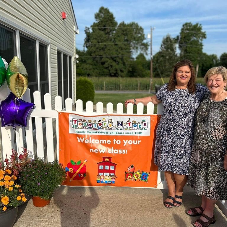 Two women standing in front of a sign that says welcome to your new class