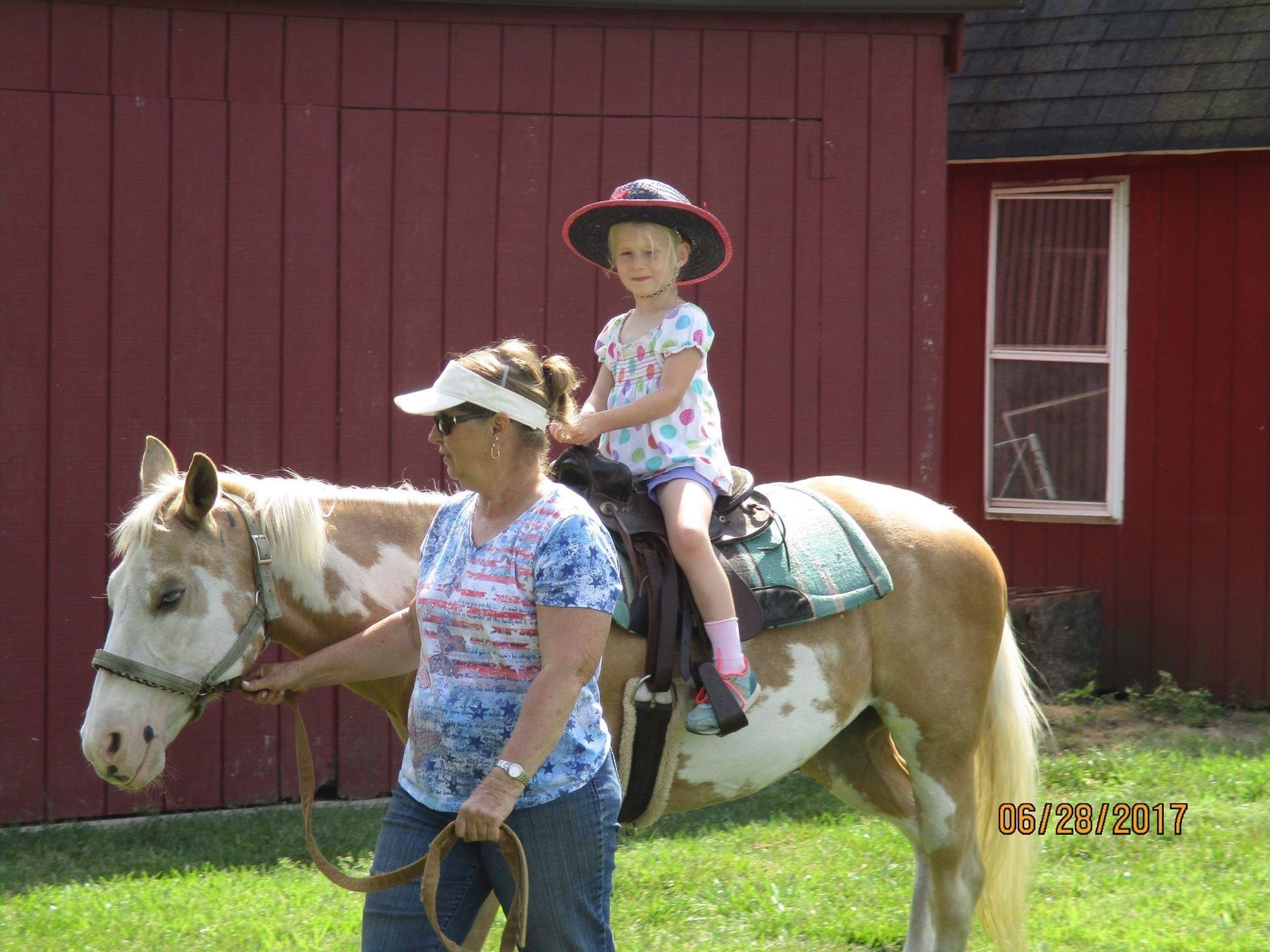 A little girl is riding on the back of a brown and white horse