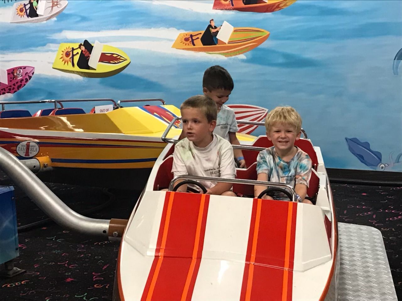 A group of young boys are riding a boat ride at an amusement park.