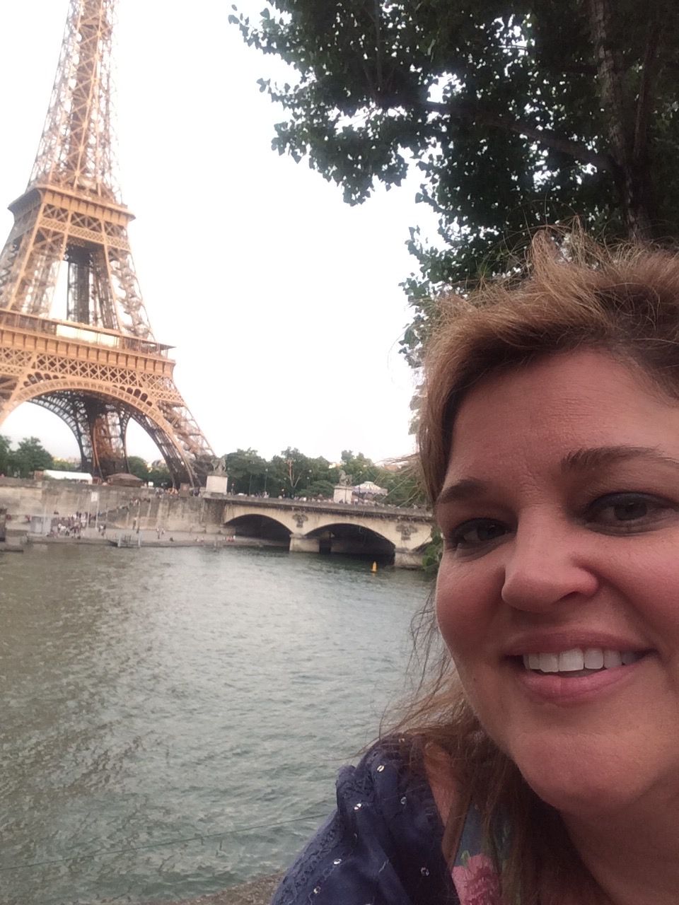 A woman is smiling in front of the eiffel tower