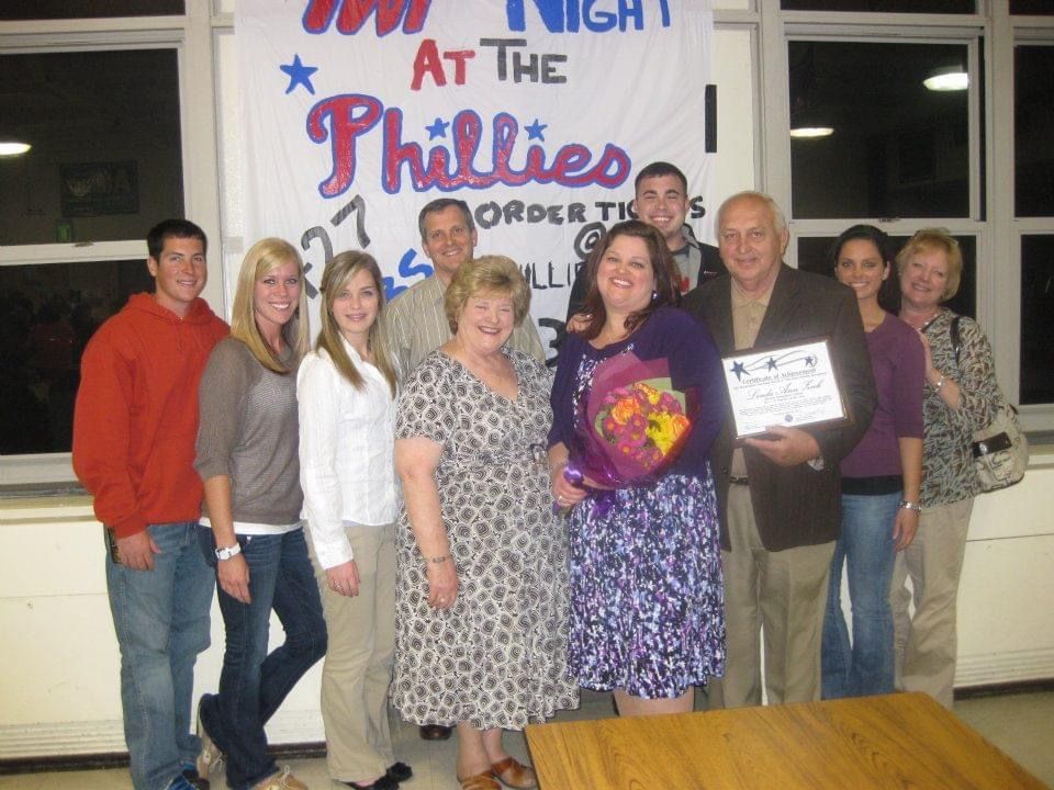 A group of people standing in front of a phillies banner