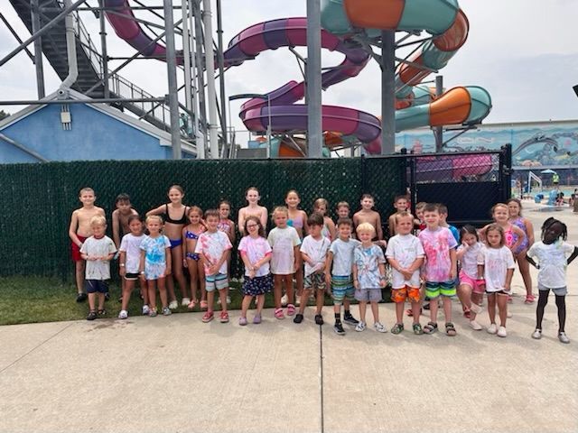 A group of children are posing for a picture in front of a water slide.
