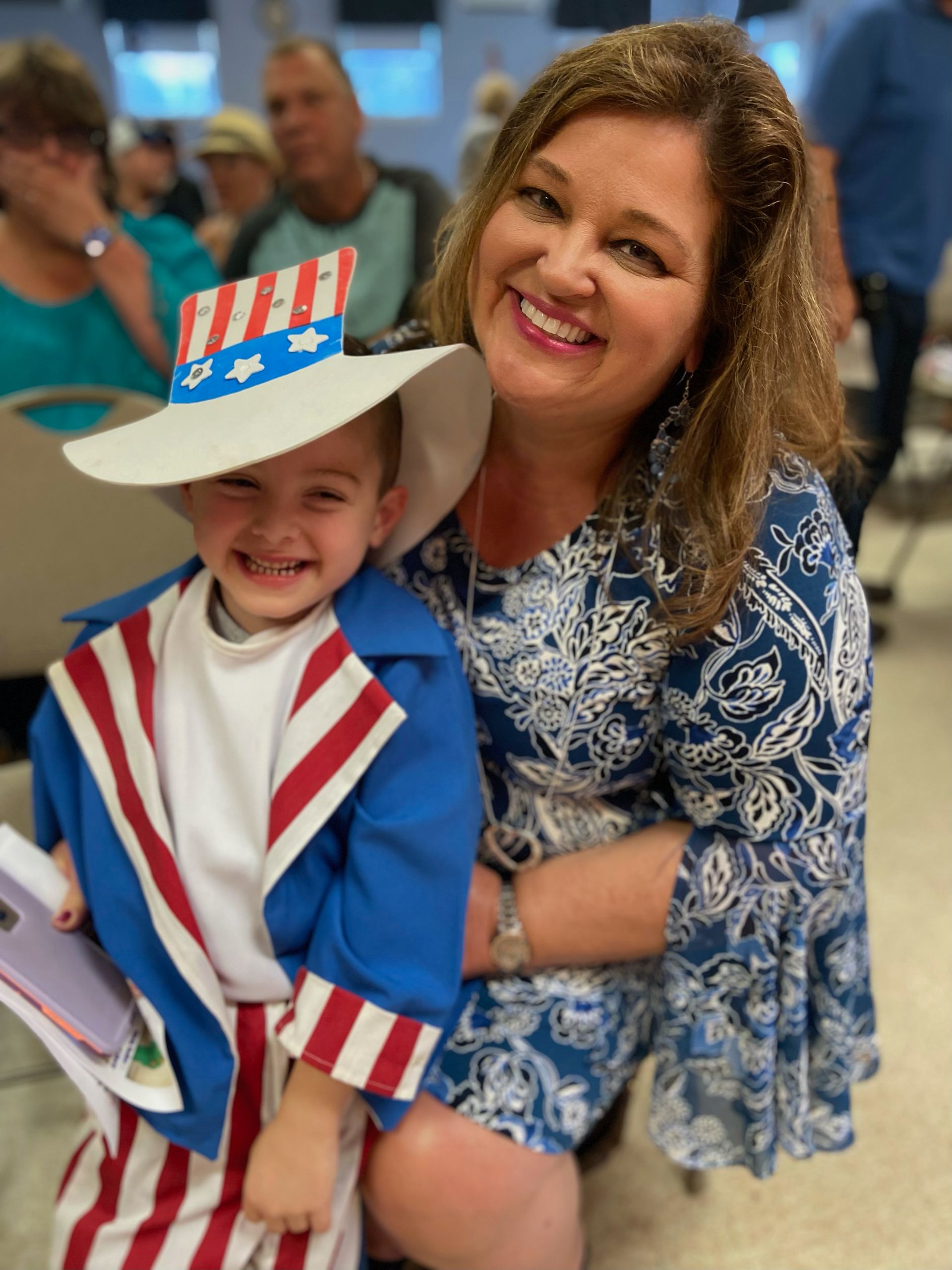 A woman is holding a child in an uncle sam costume