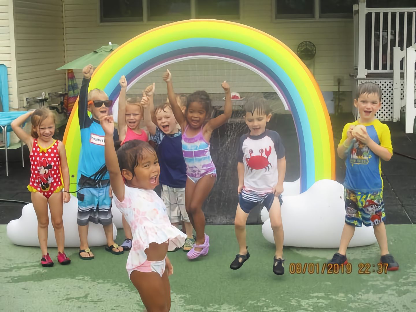 A group of children are standing in front of an inflatable rainbow.