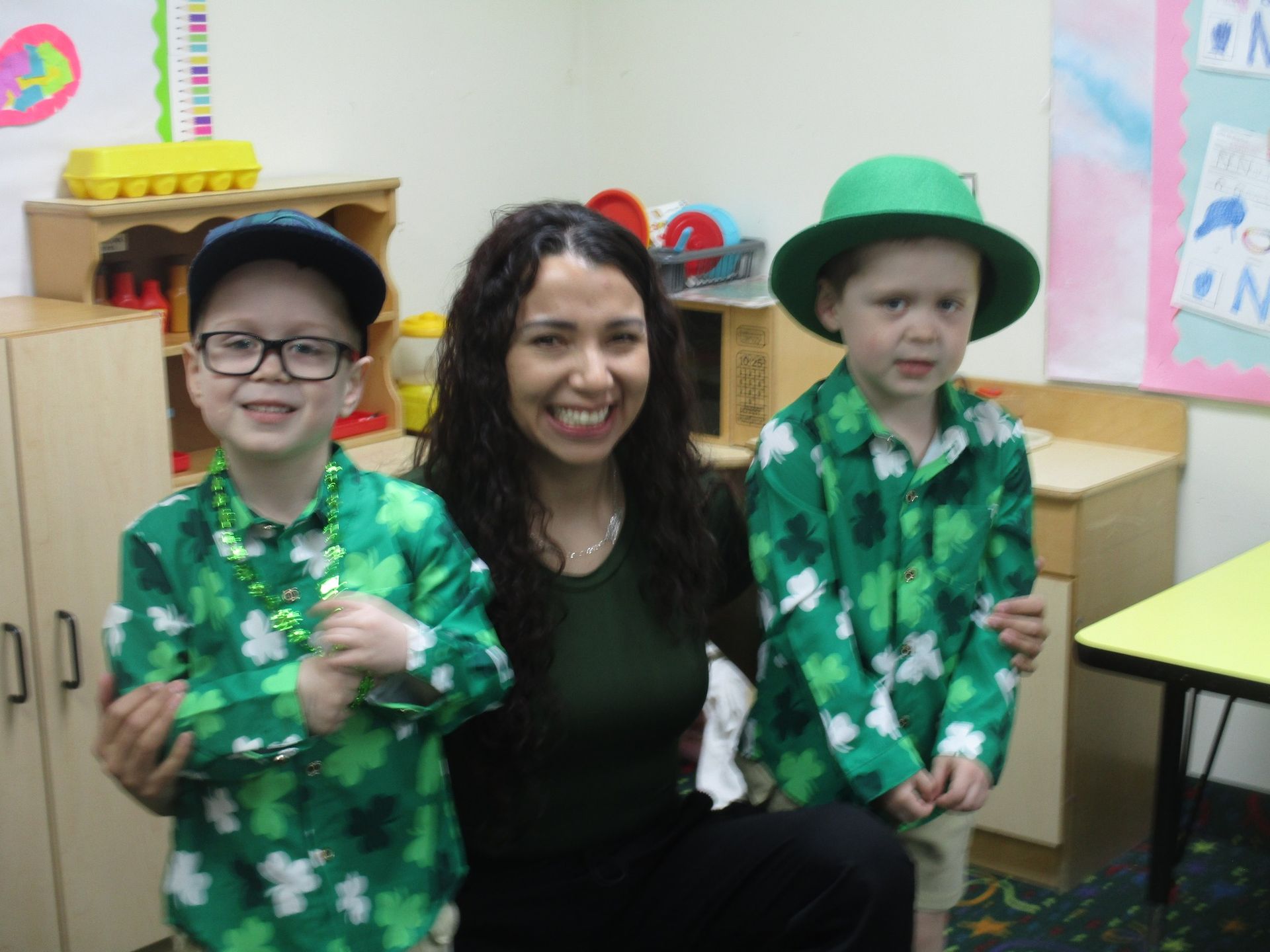 A woman is posing for a picture with two children dressed in green