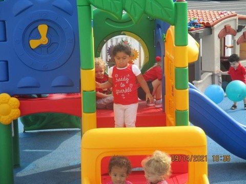 A little girl wearing a red shirt that says i love you is playing on a playground