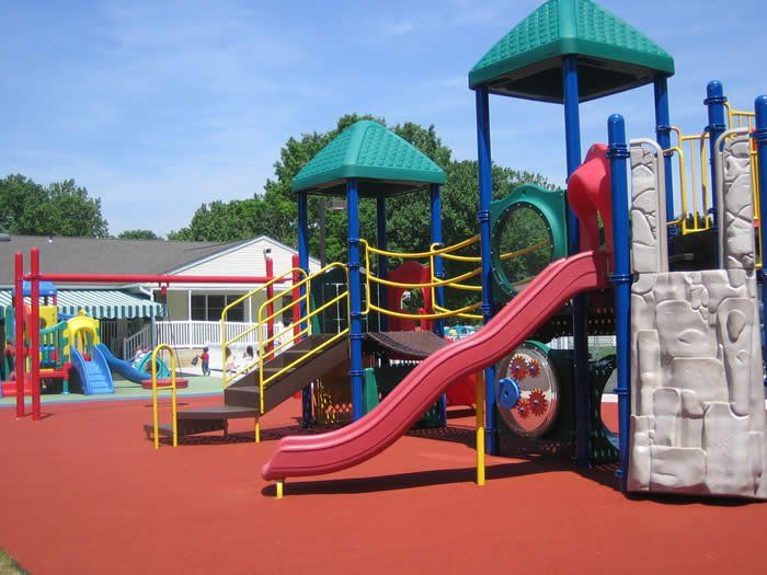 A playground with a red slide and a green roof