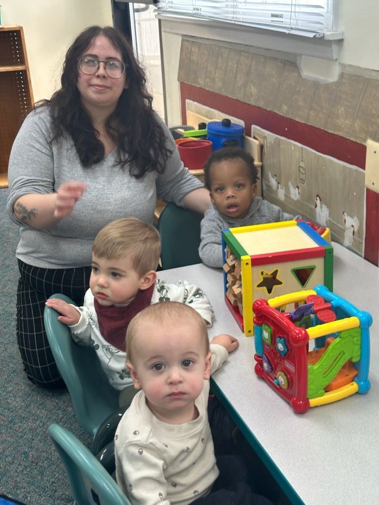 A woman next to two children sitting at a table with toys