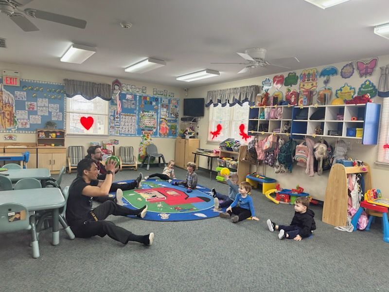 A group of children are sitting on the floor in a classroom