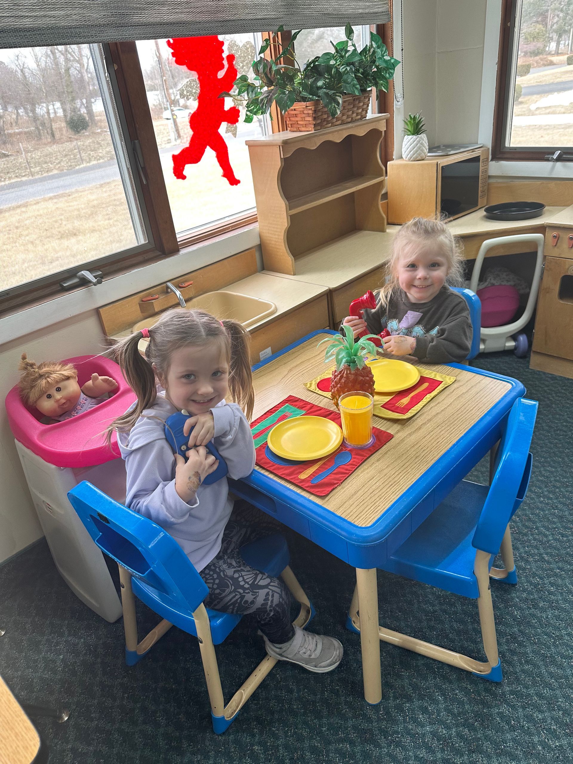 Two little girls are sitting at a table with plates and cups.