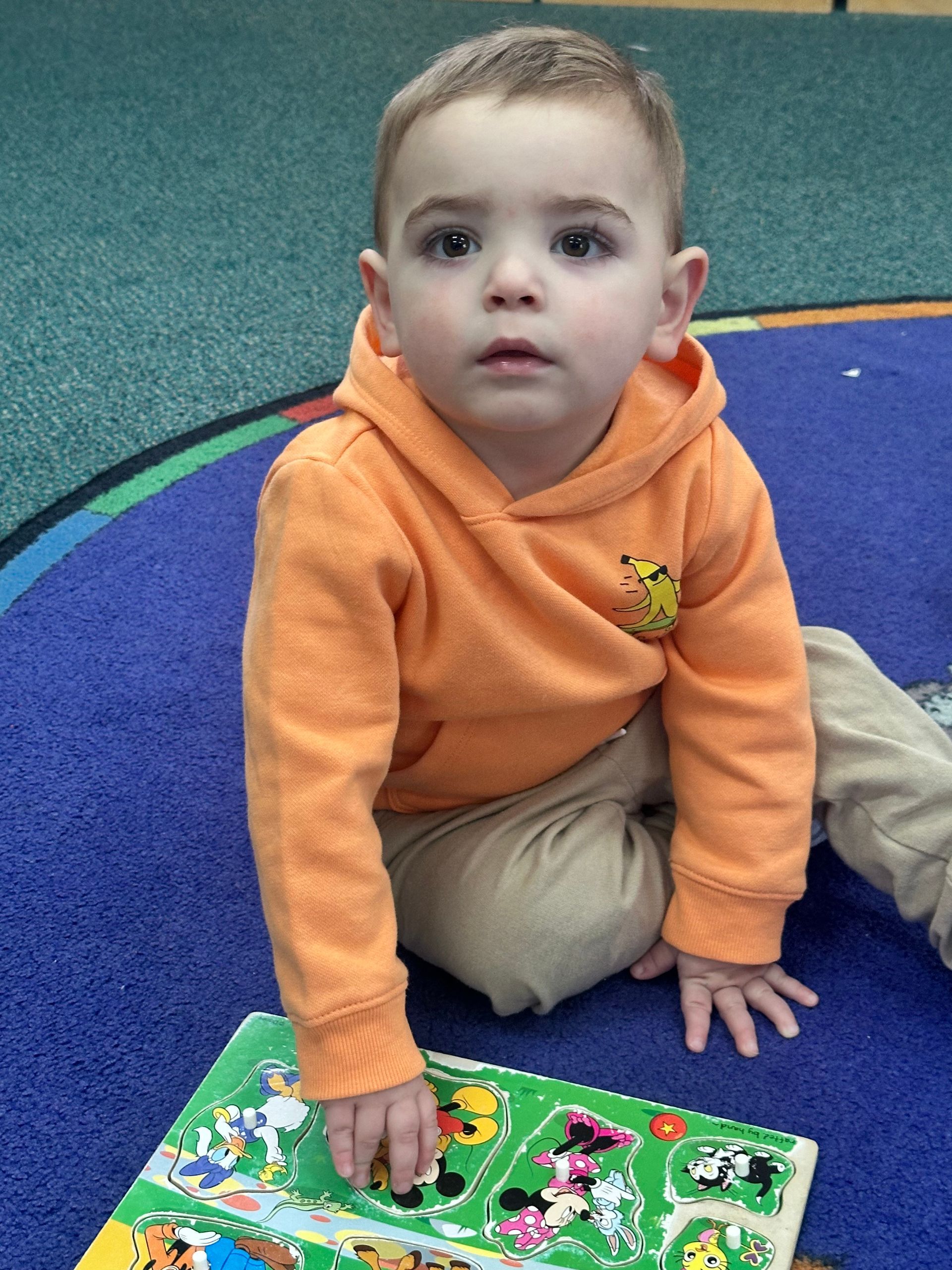 A young boy is sitting on the floor playing with a puzzle