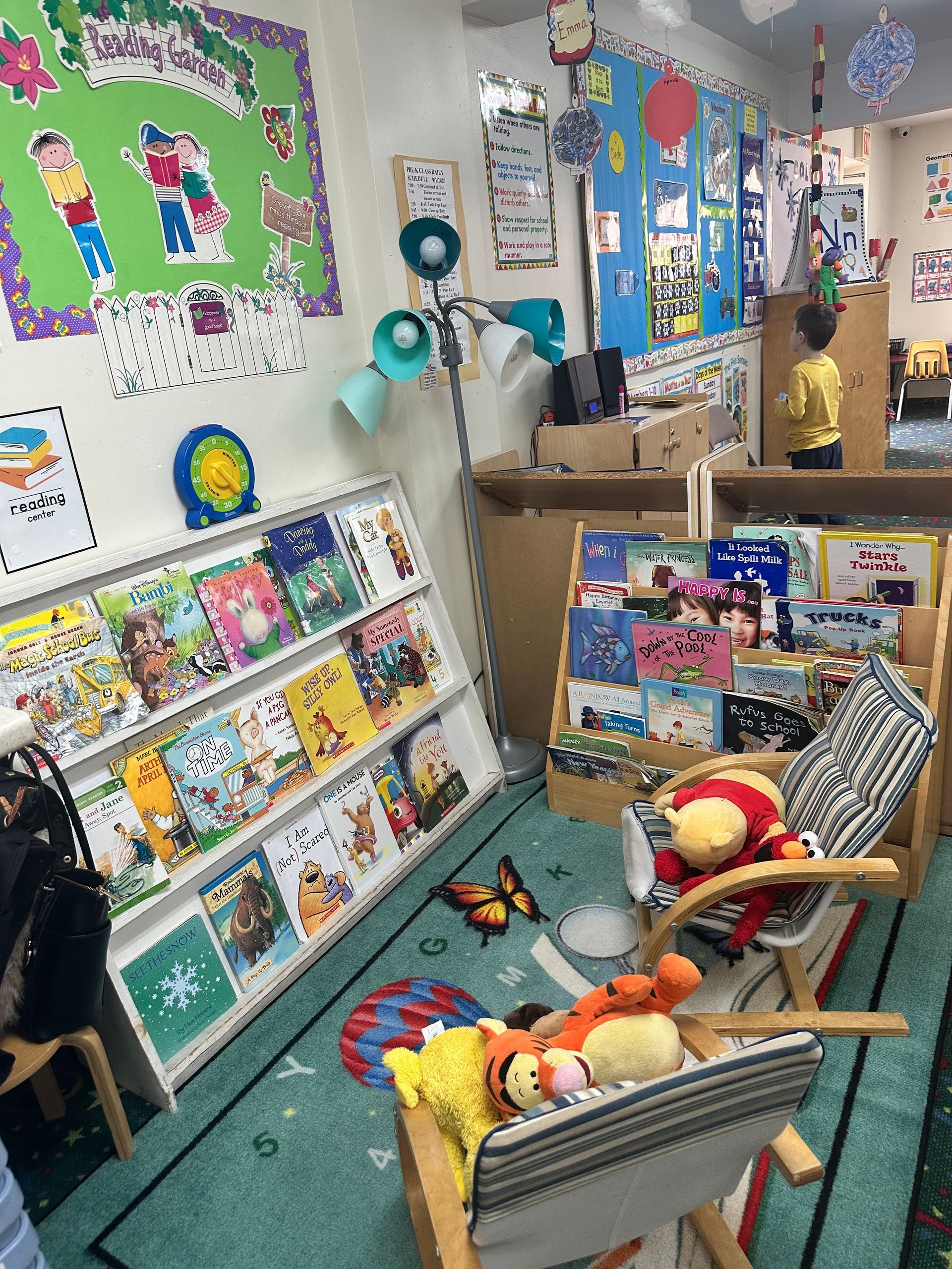 A classroom with a lot of books on shelves and chairs.