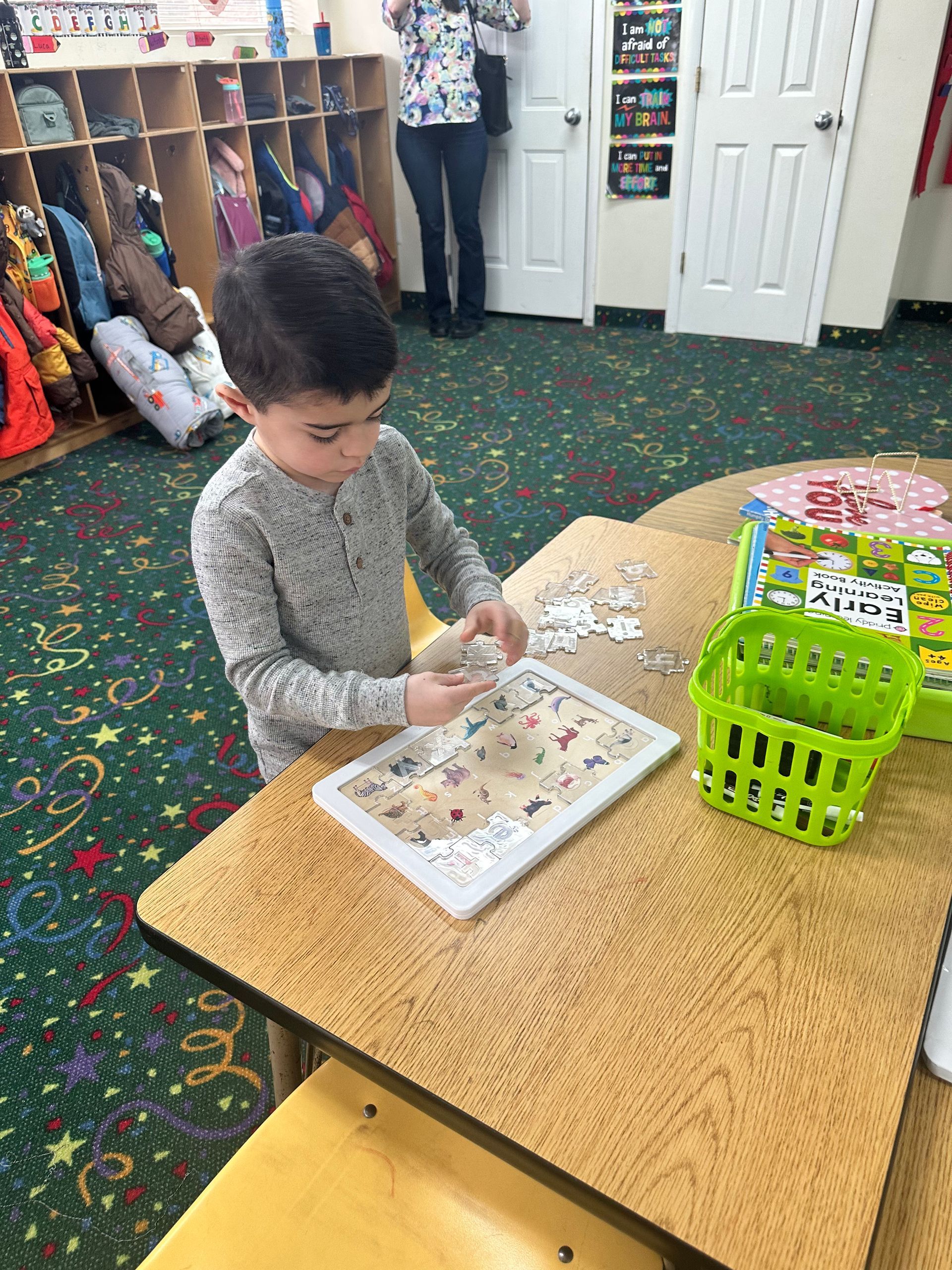 A young boy is sitting at a table playing with puzzles.