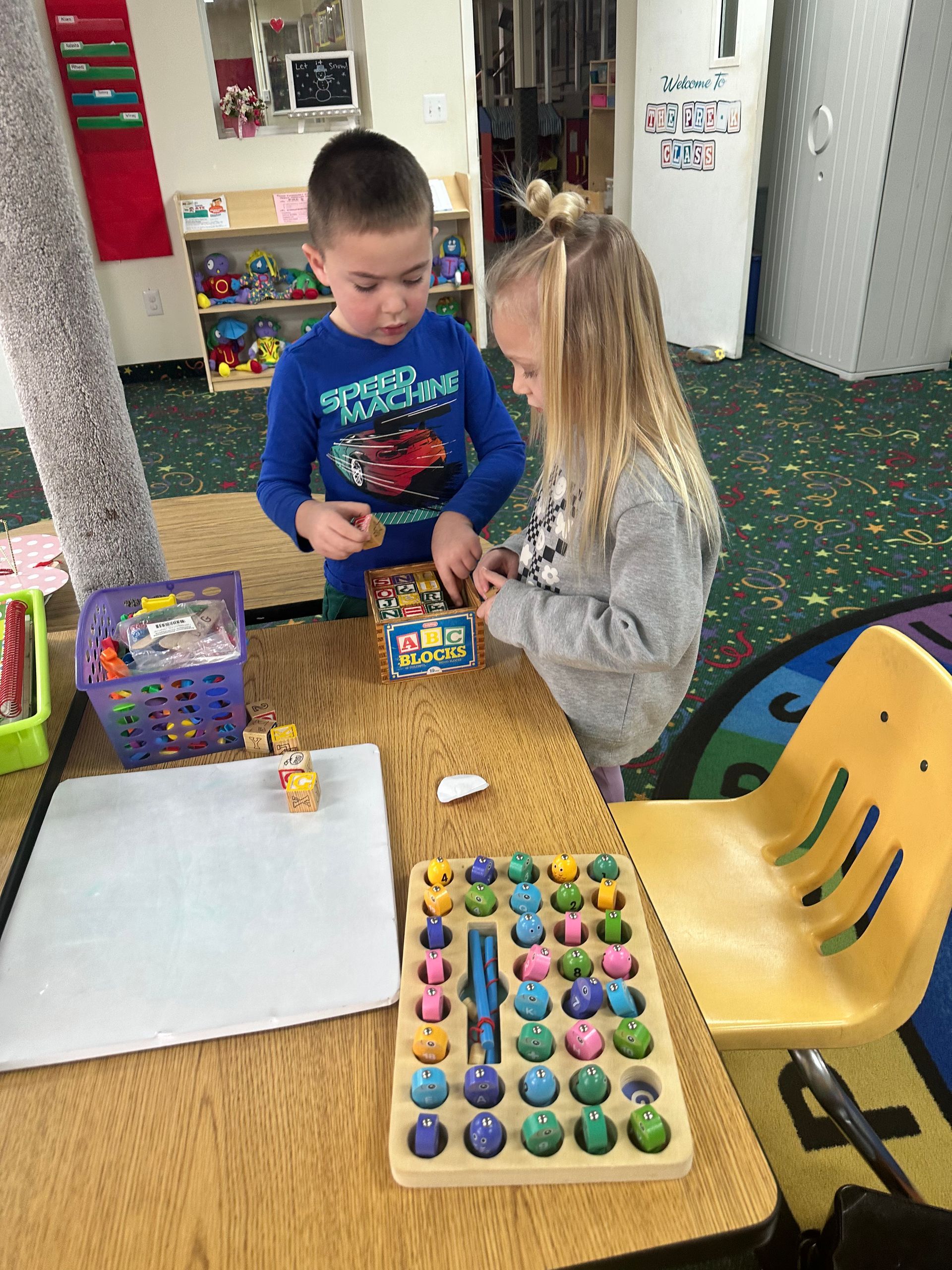 A boy and a girl are playing with toys at a table.