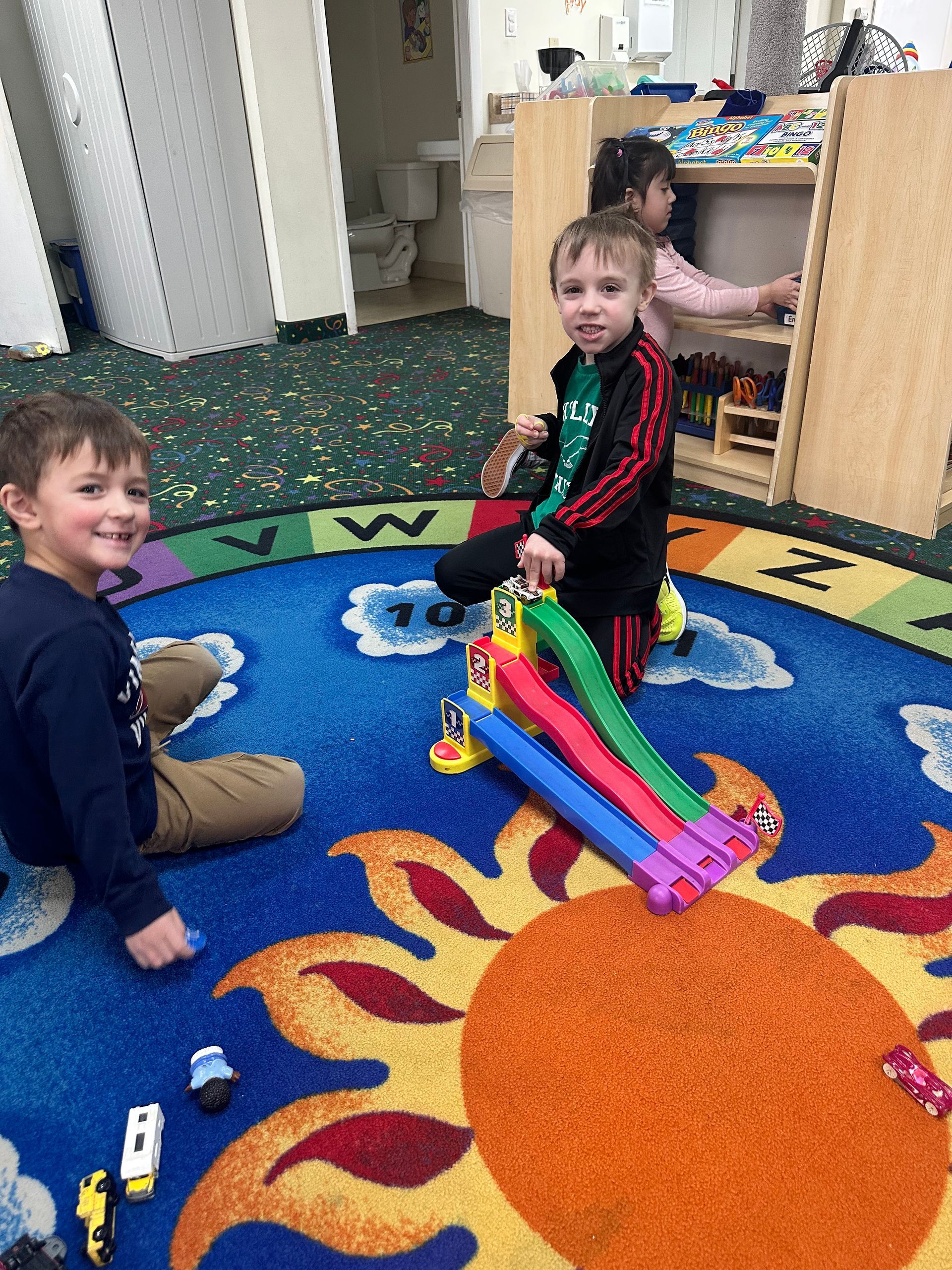 Two young boys are sitting on the floor playing with toys.