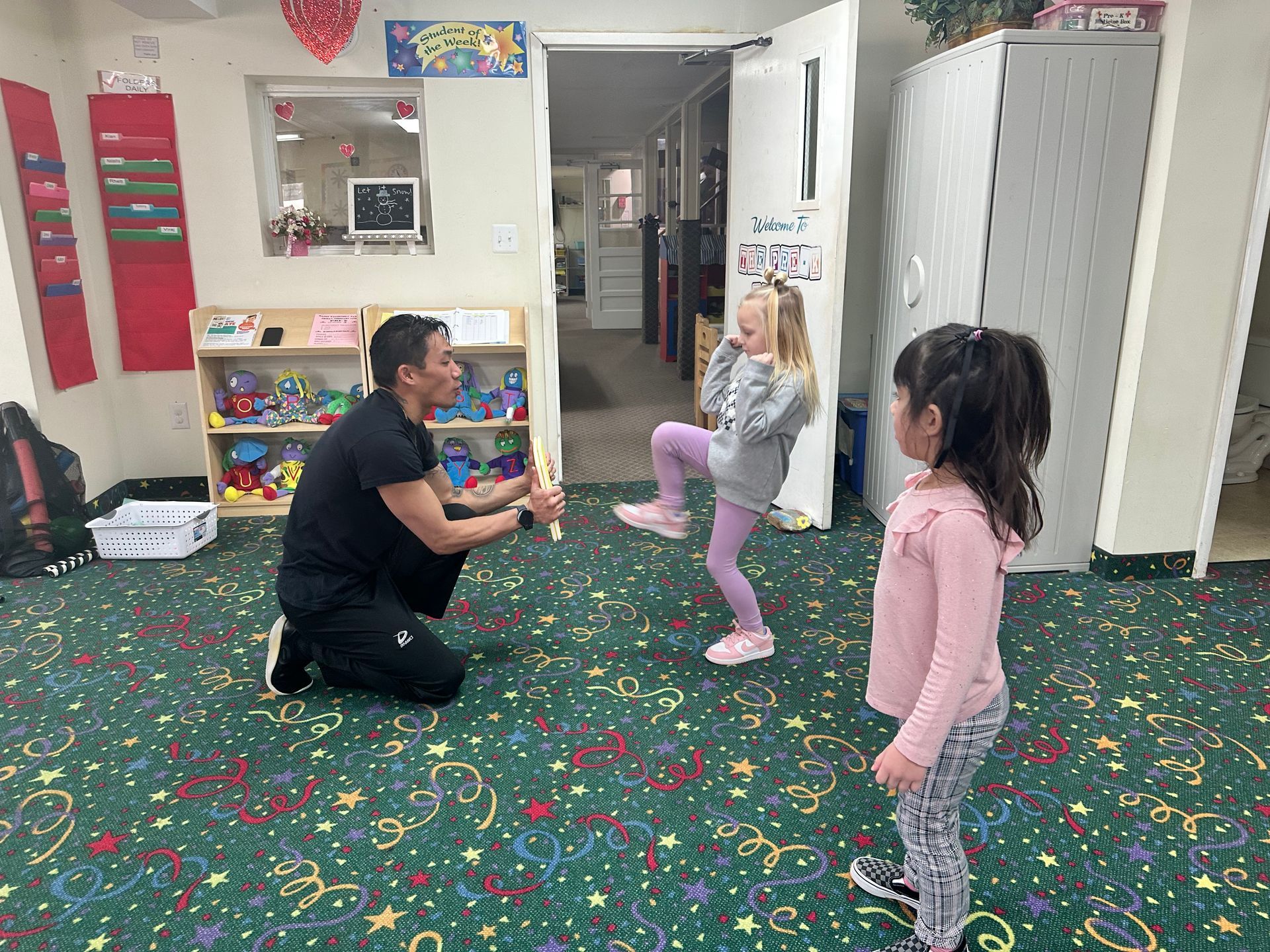 A man is kneeling down in a room with two little girls.