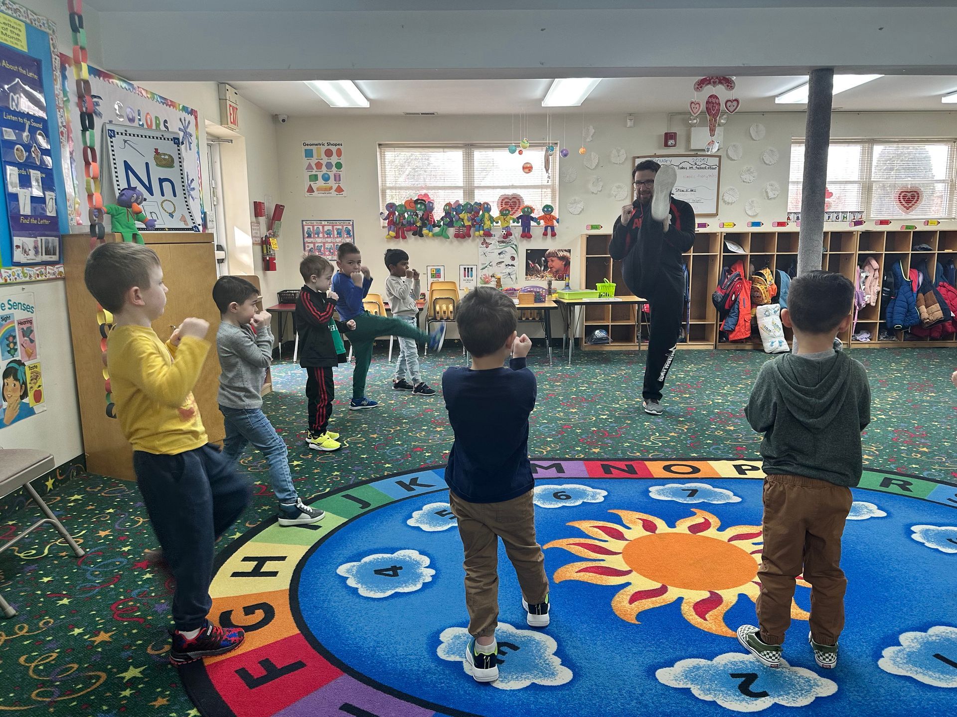 A group of children are standing in a circle in a classroom.