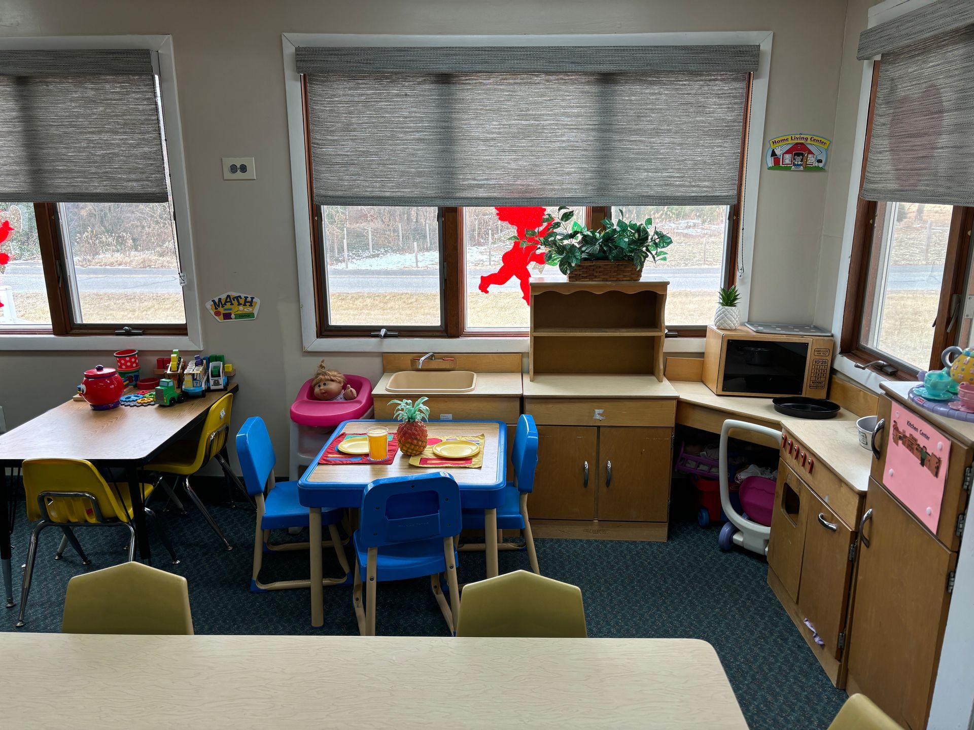 A classroom with tables and chairs and a kitchen.