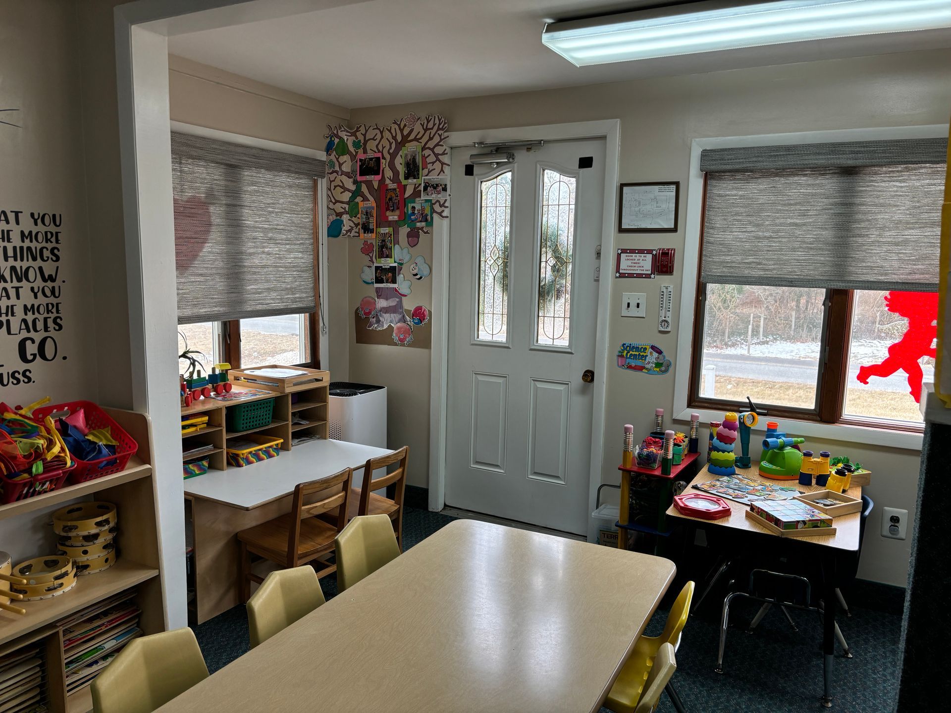 A classroom with a table and chairs and a door.
