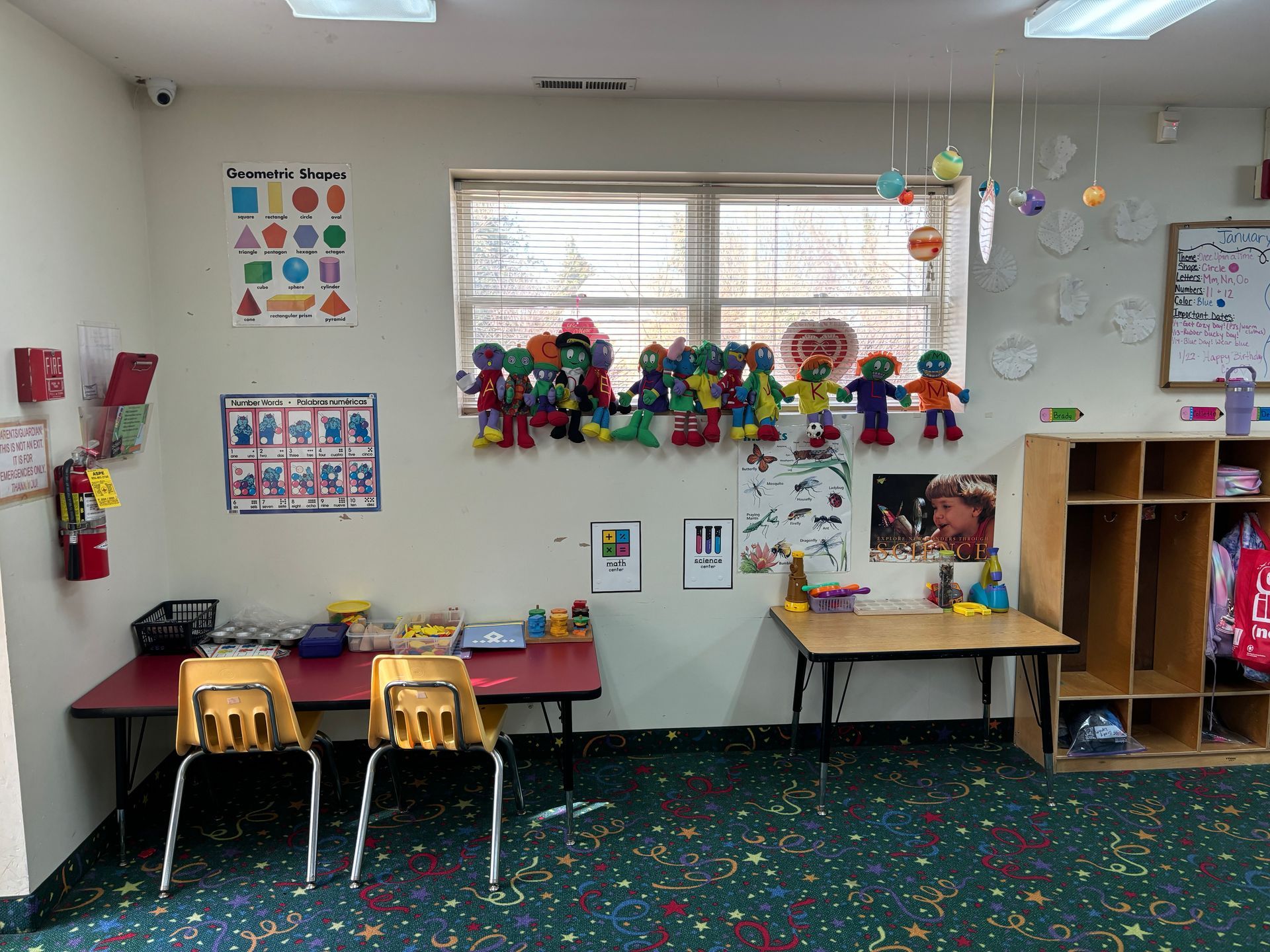 A classroom with a lot of toys on the wall and a table and chairs.