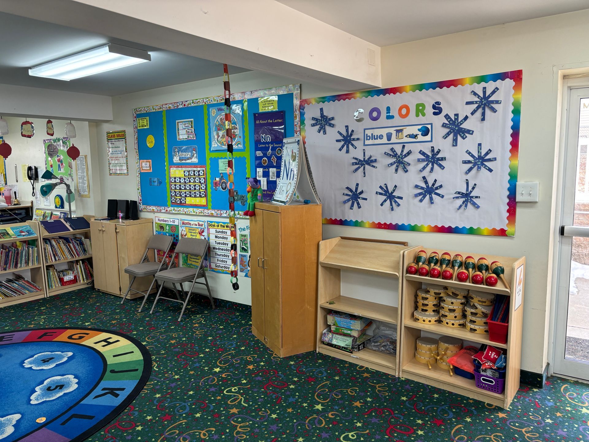 A classroom with a bulletin board that says colors on it.