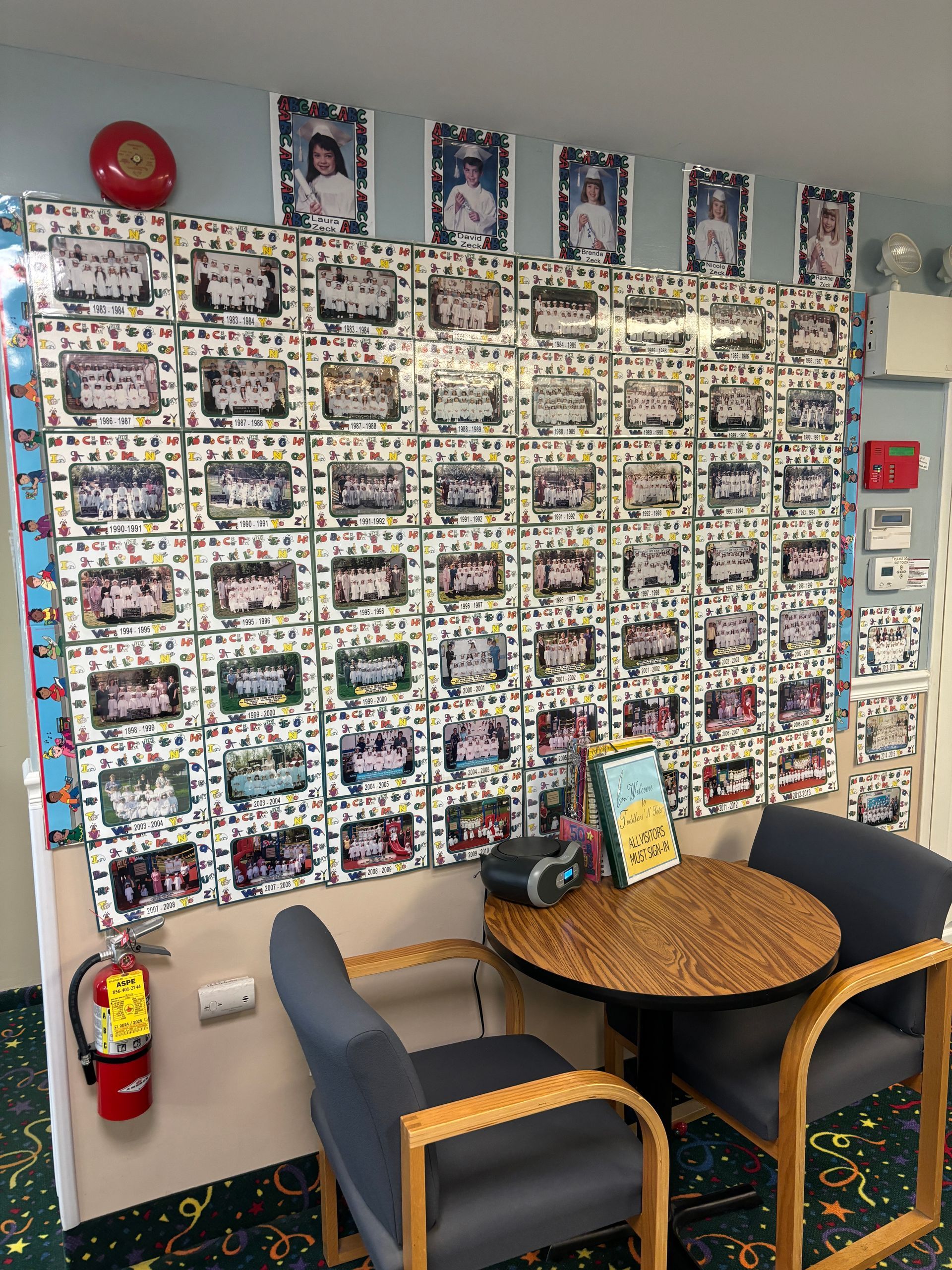 A room with two chairs and a table with a fire extinguisher on the wall.