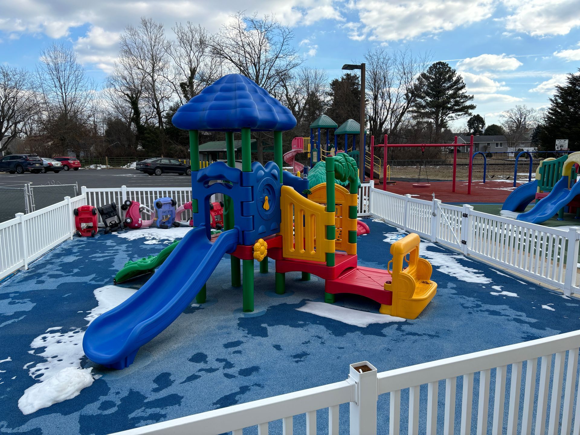 A colorful playground with a white fence around it.