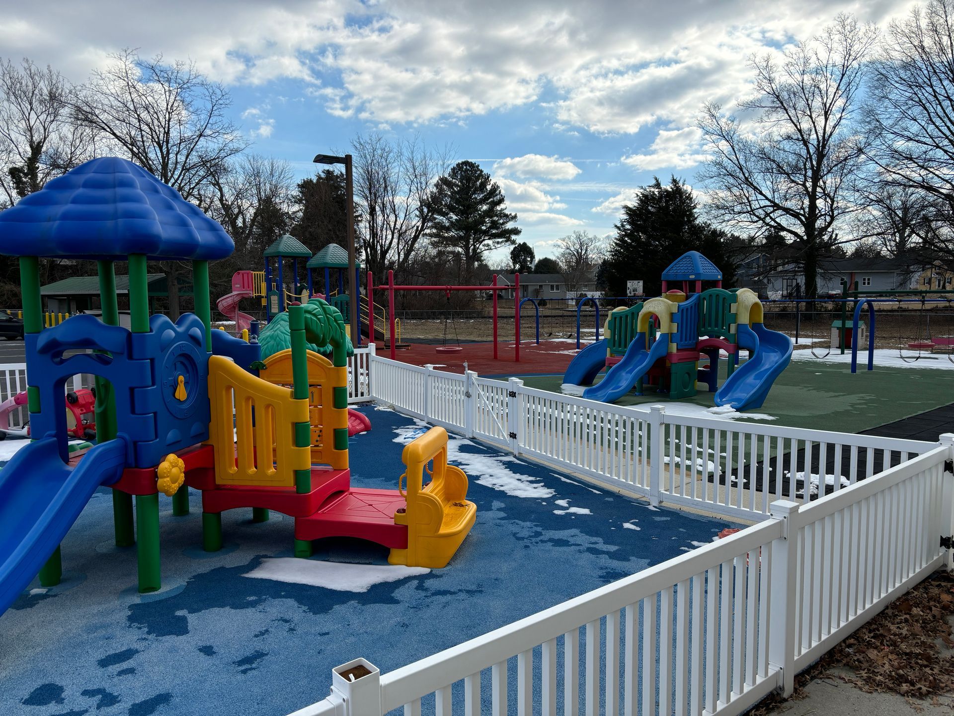 A colorful playground with a white fence surrounding it
