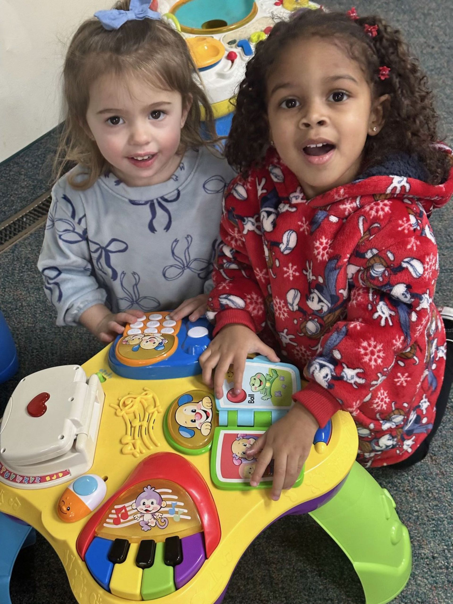 Two young girls playing with a colorful activity table