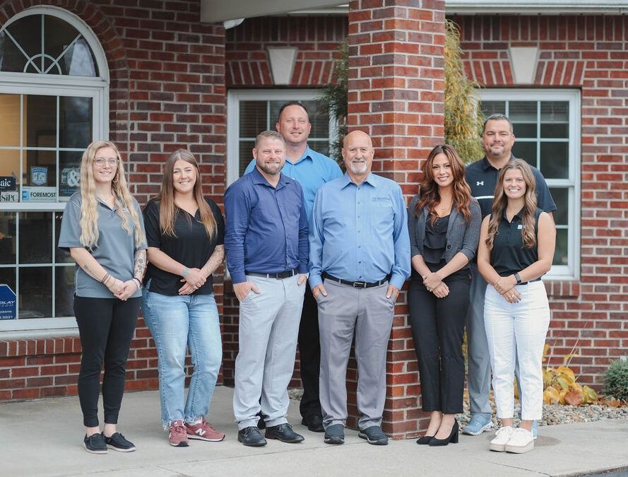 A group of people are posing for a picture in front of a brick building.