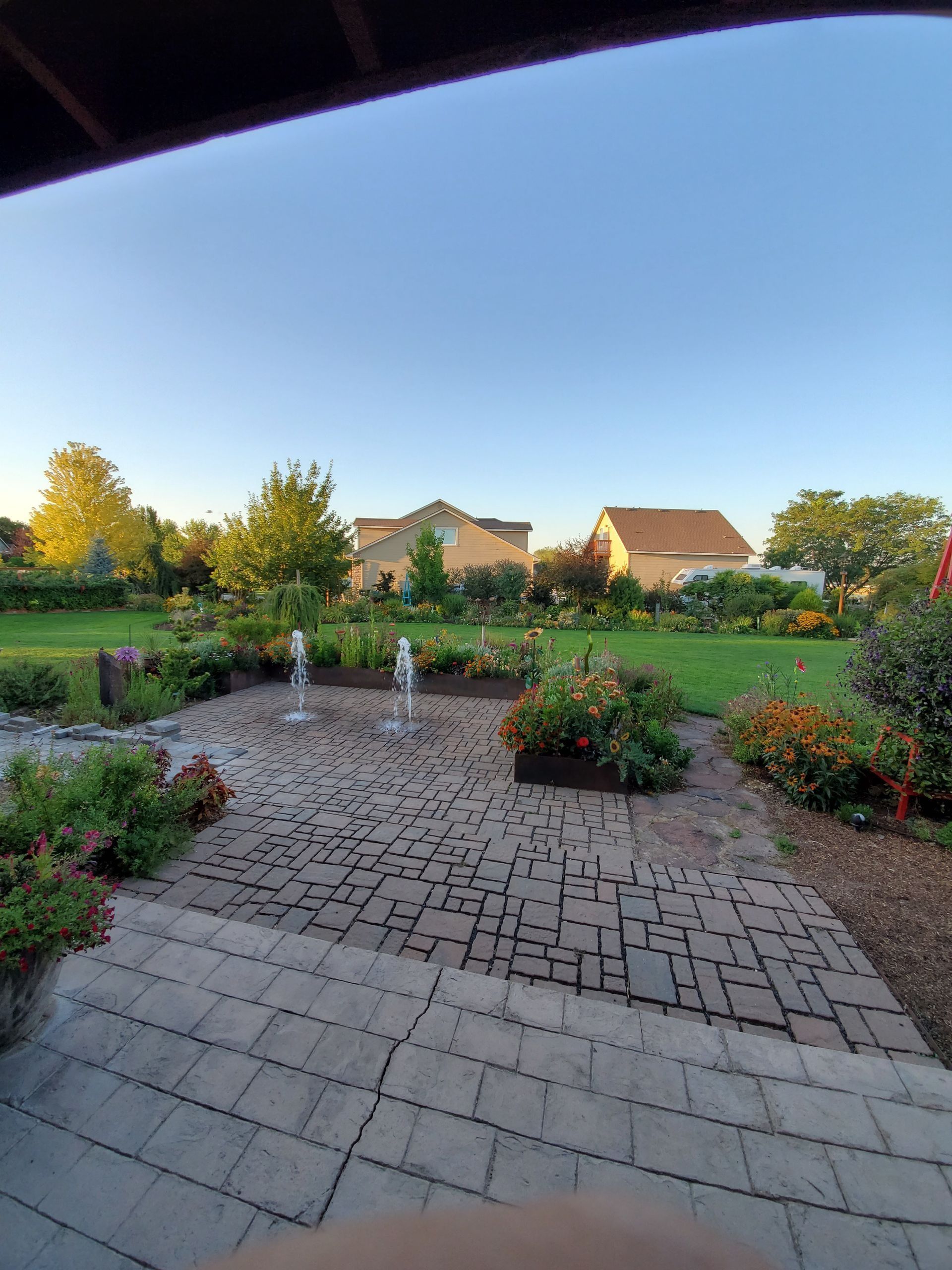 Patio with water fountain, garden, and houses on a sunny day.