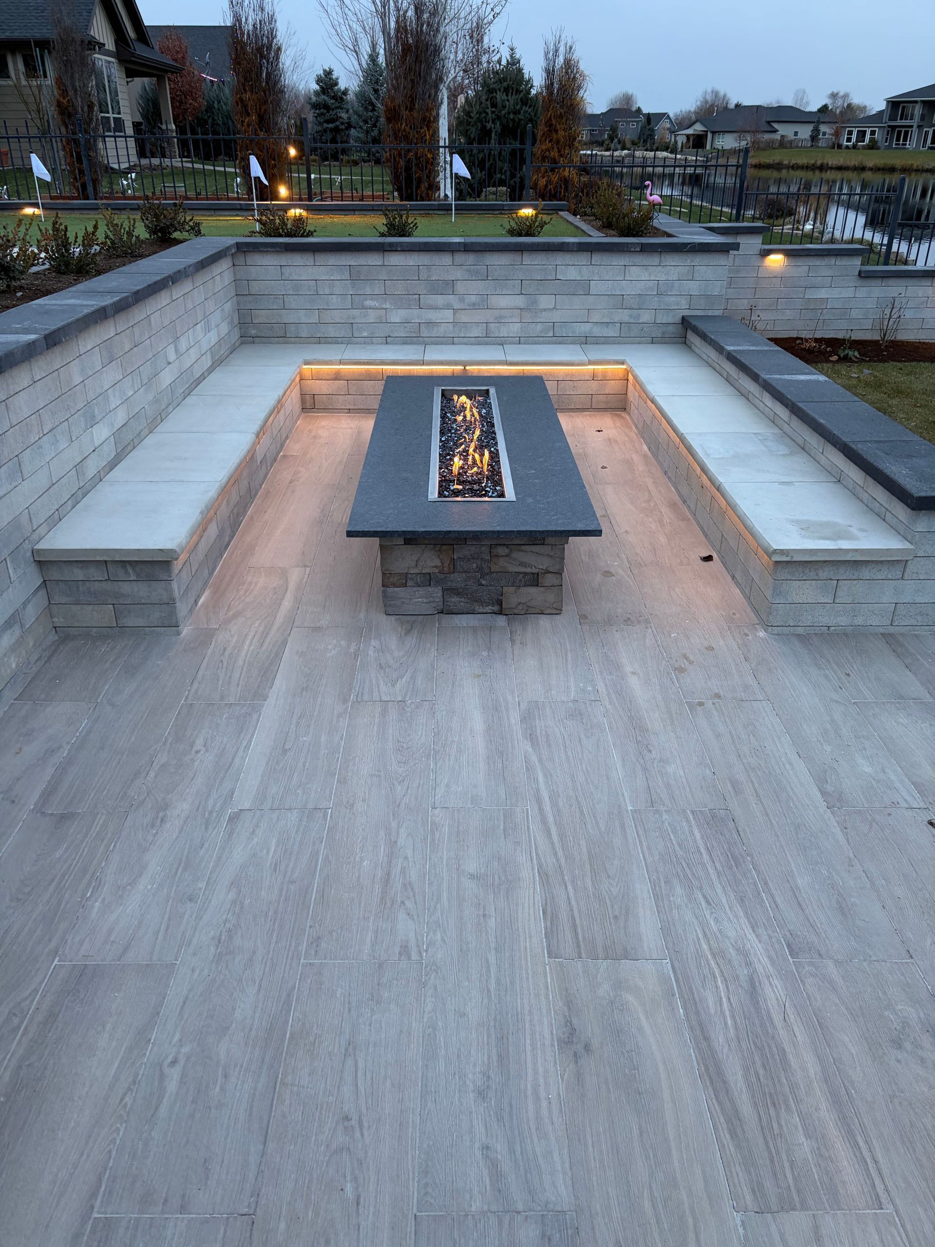 Outdoor patio with a rectangular fire pit surrounded by concrete benches.