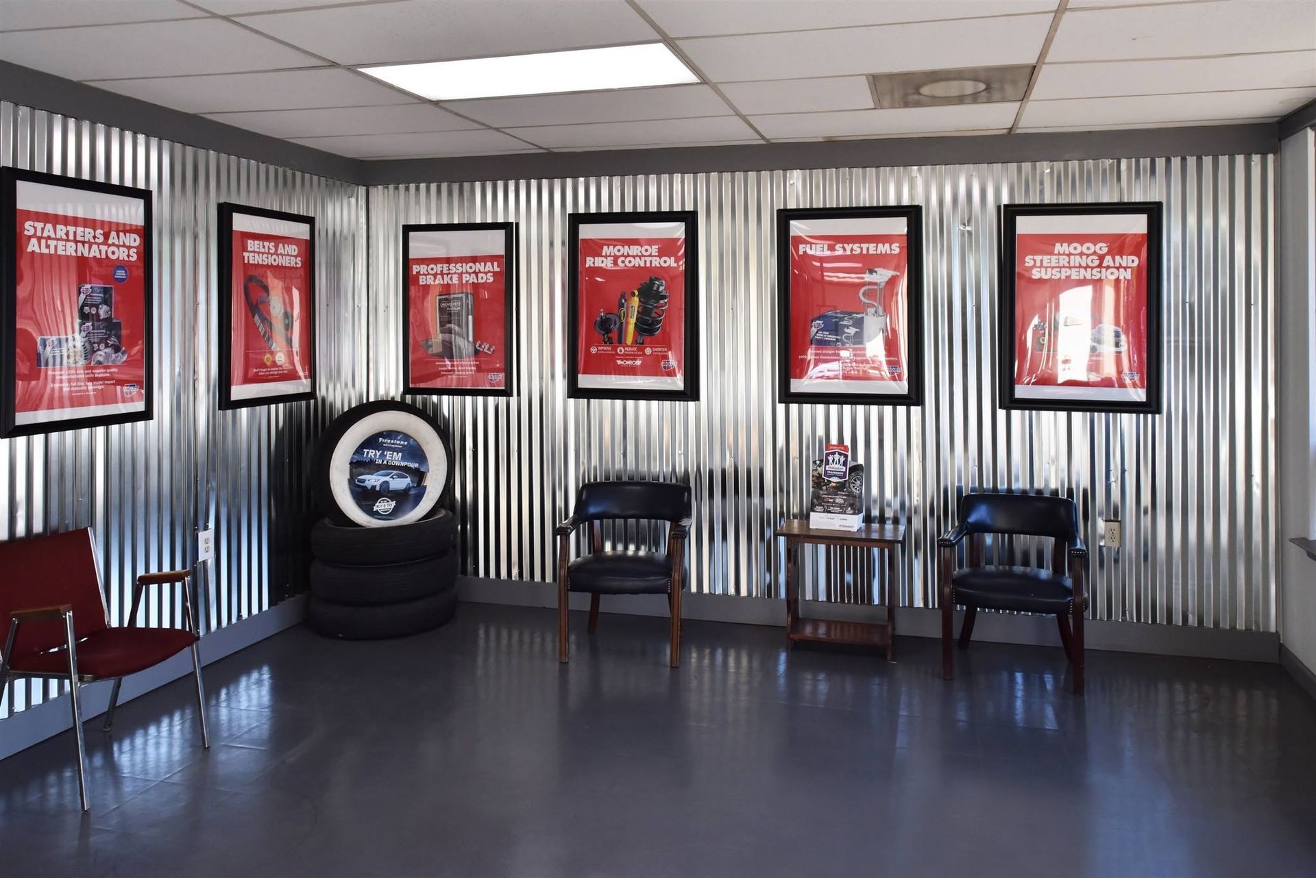 Waiting area with black chairs, framed red posters, and corrugated metal walls
