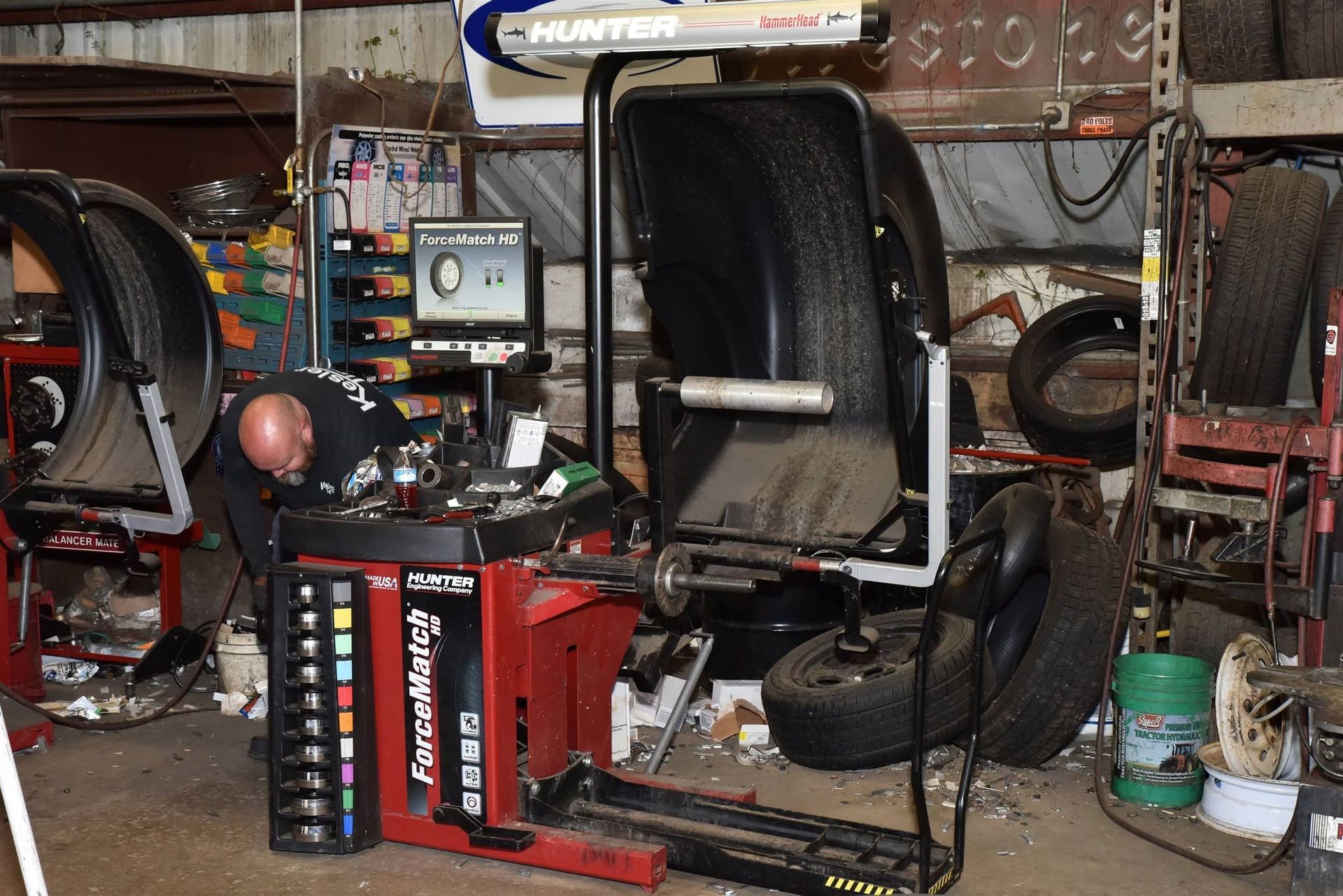 Auto repair shop with a red tire-changing machine and stacked tires under a car lift