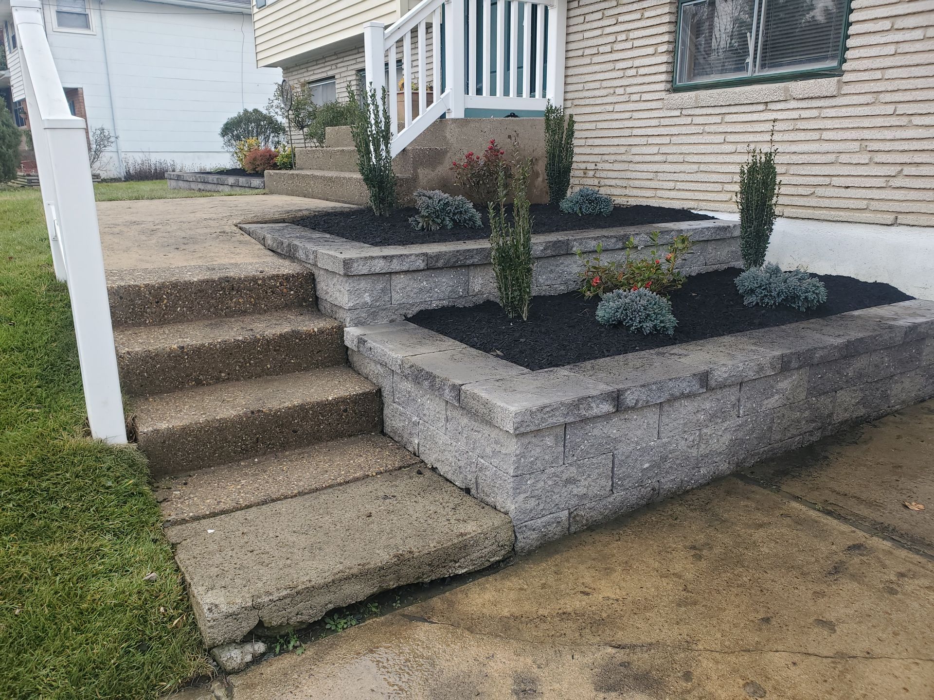 A brick wall with a planter and stairs in front of a house.