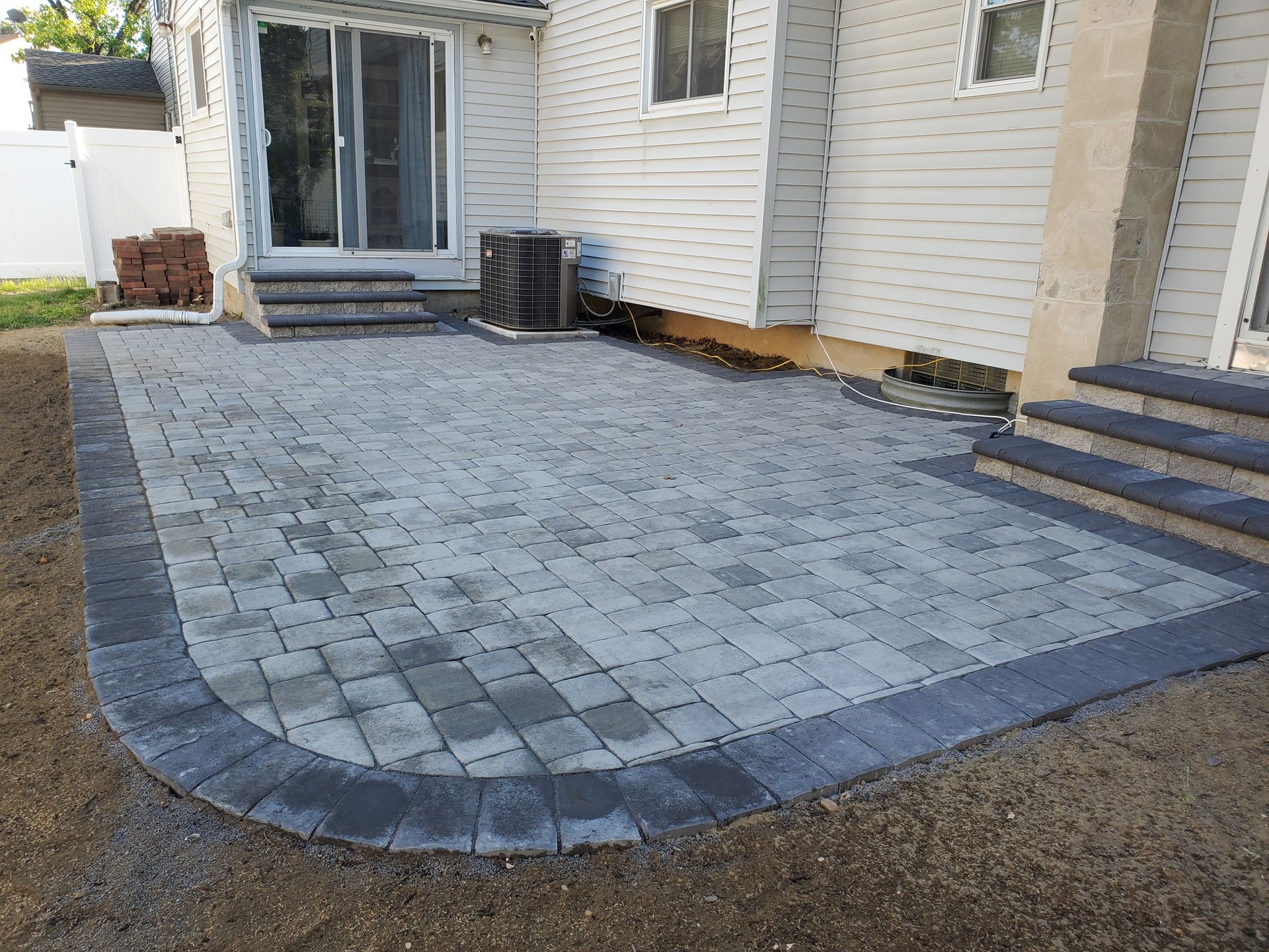 A patio with steps and a sliding glass door in front of a house.