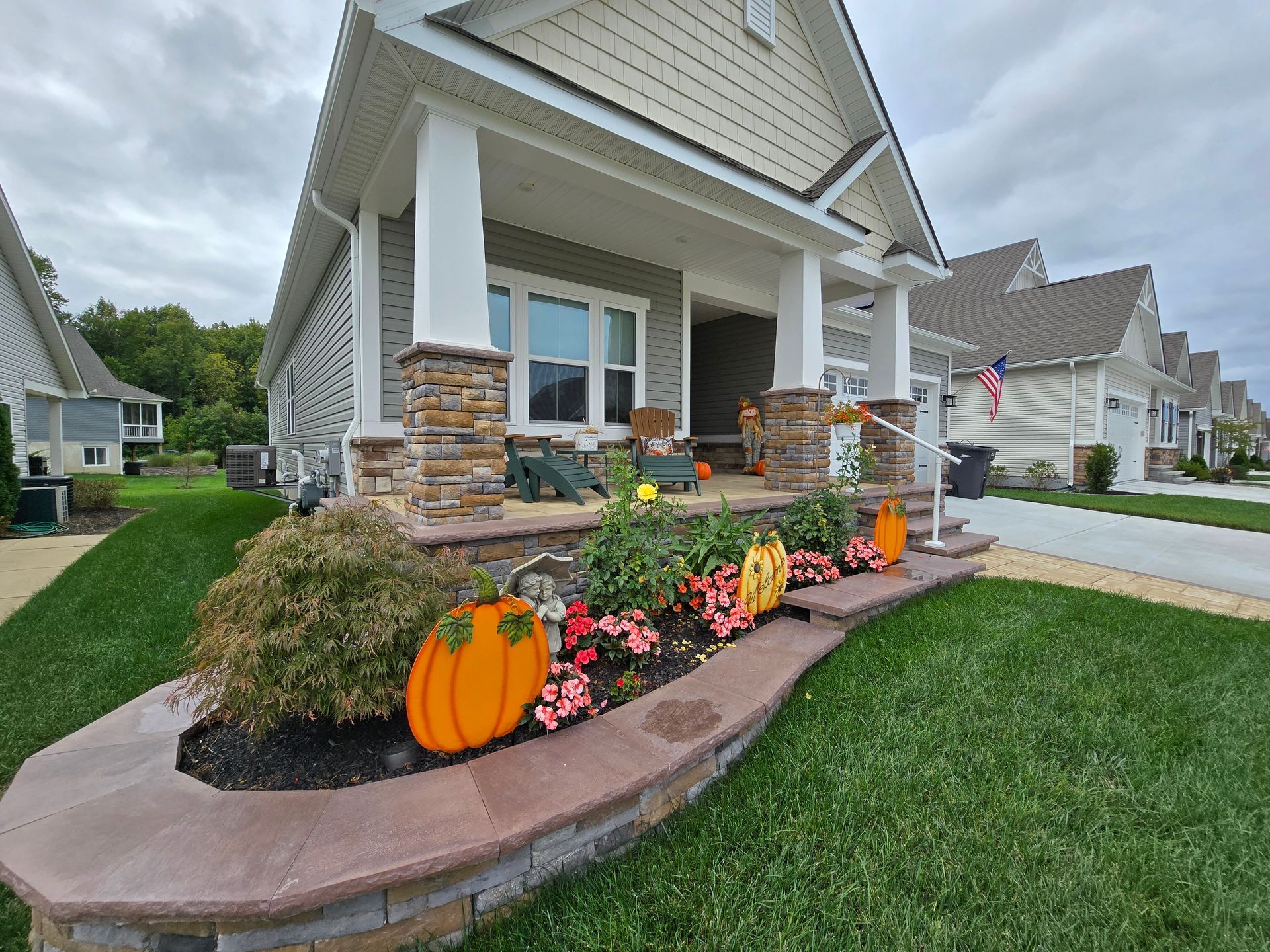 A house with a porch decorated for fall with pumpkins and flowers.