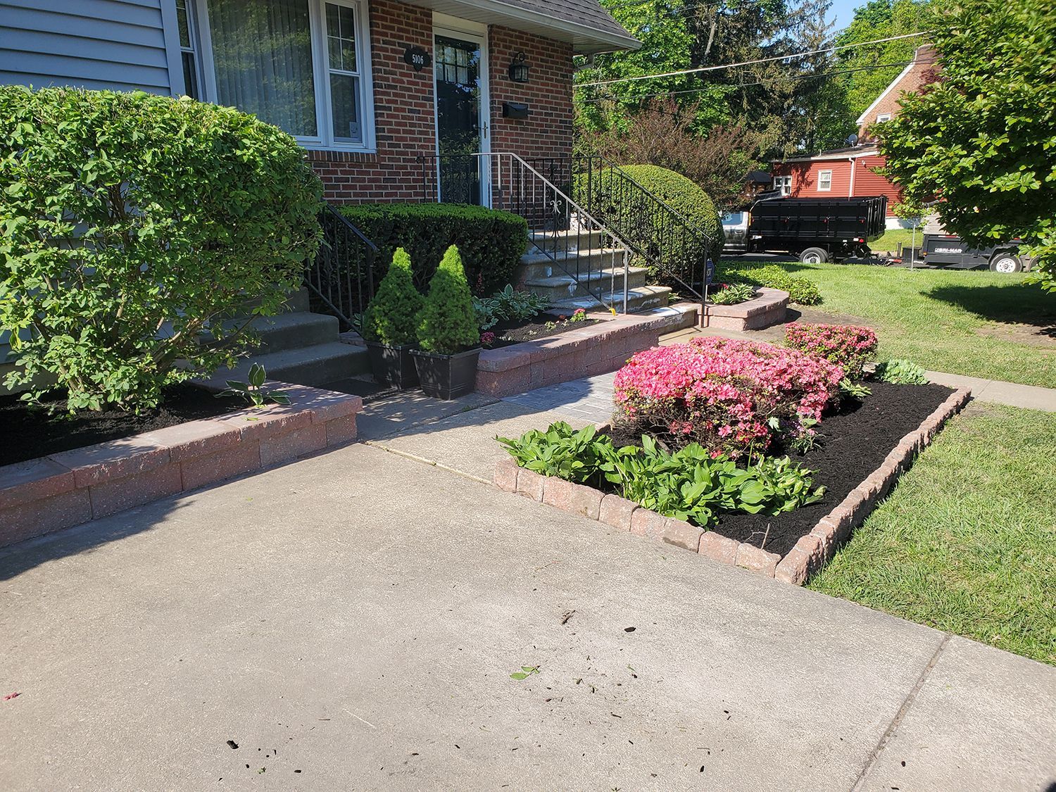 A brick house with a sidewalk and flowers in front of it