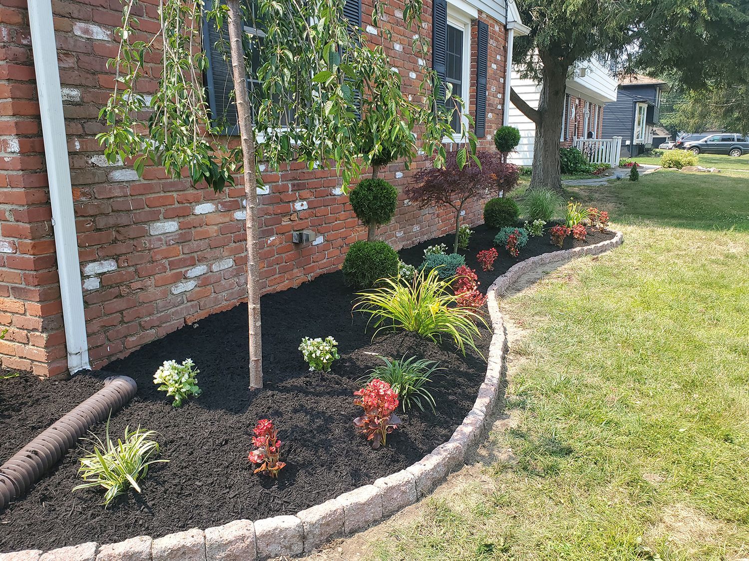 A car is parked in front of a house next to a garden.