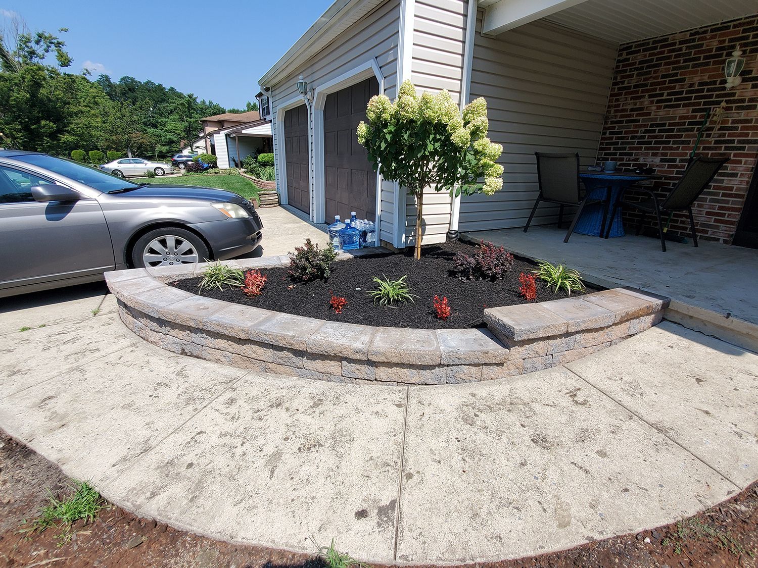 A car is parked in front of a house next to a garden.