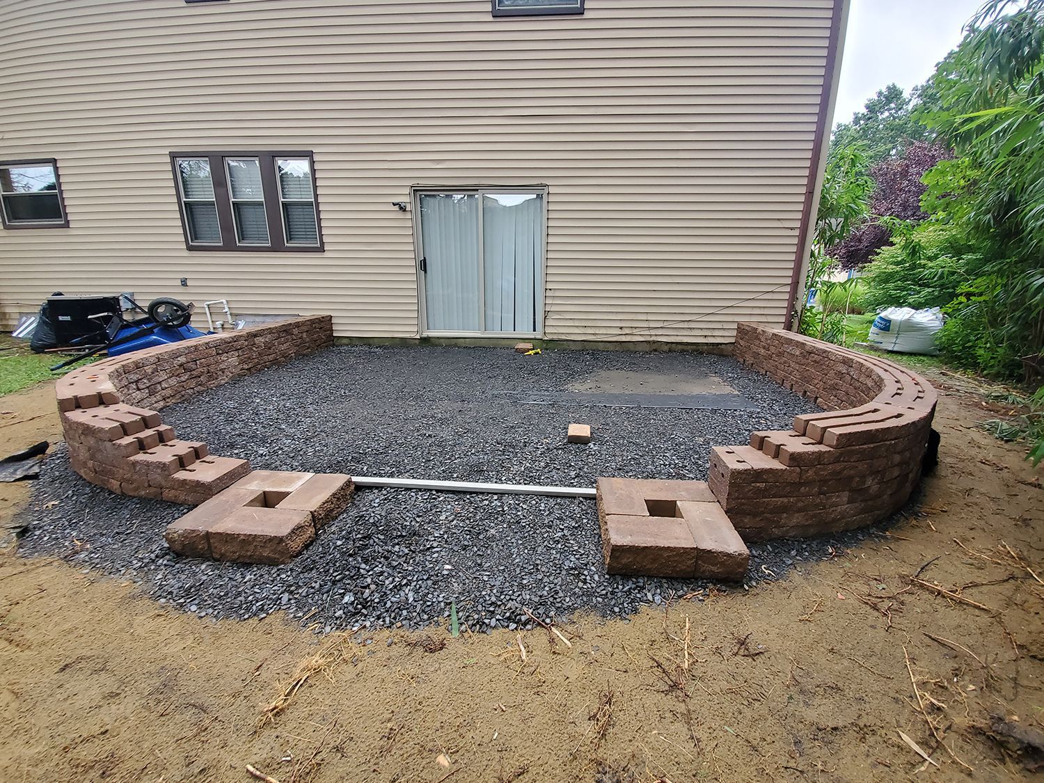 A brick wall is being built in the backyard of a house.