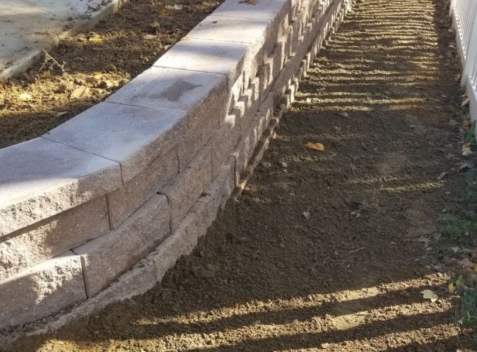 A brick wall is surrounded by dirt and grass