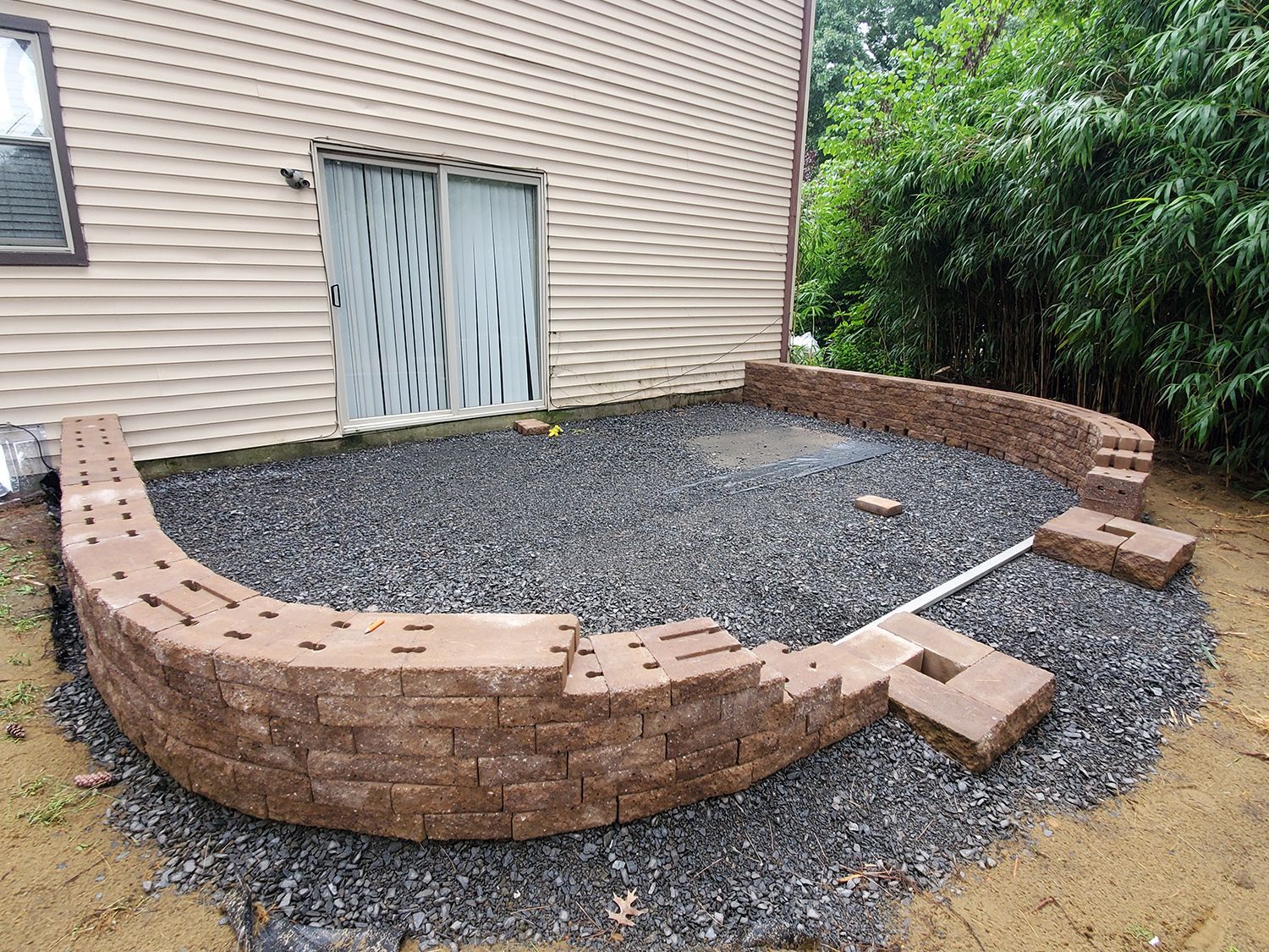 A brick wall is being built in the backyard of a house.