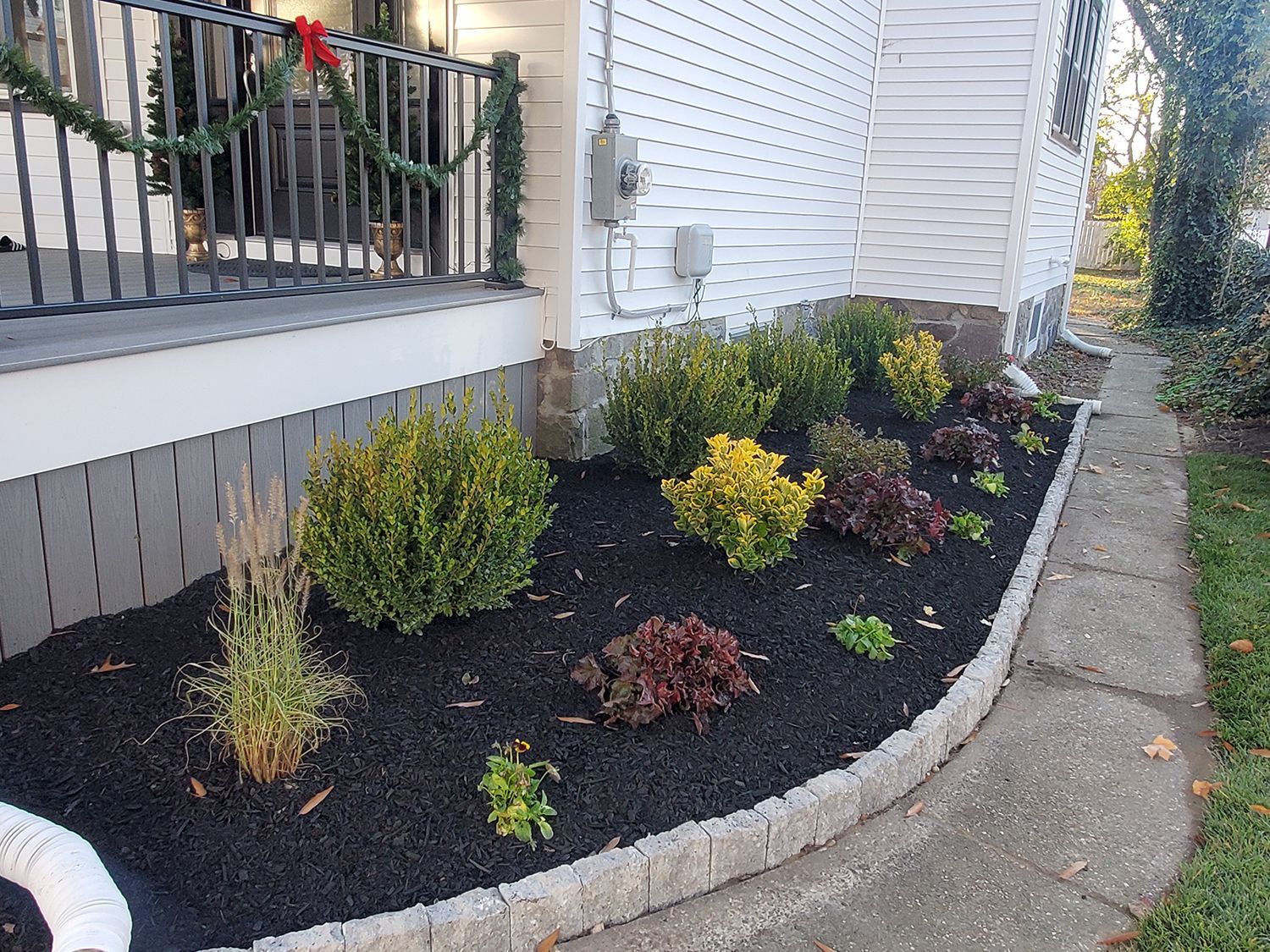 A sidewalk leading to a house with a garden in front of it.
