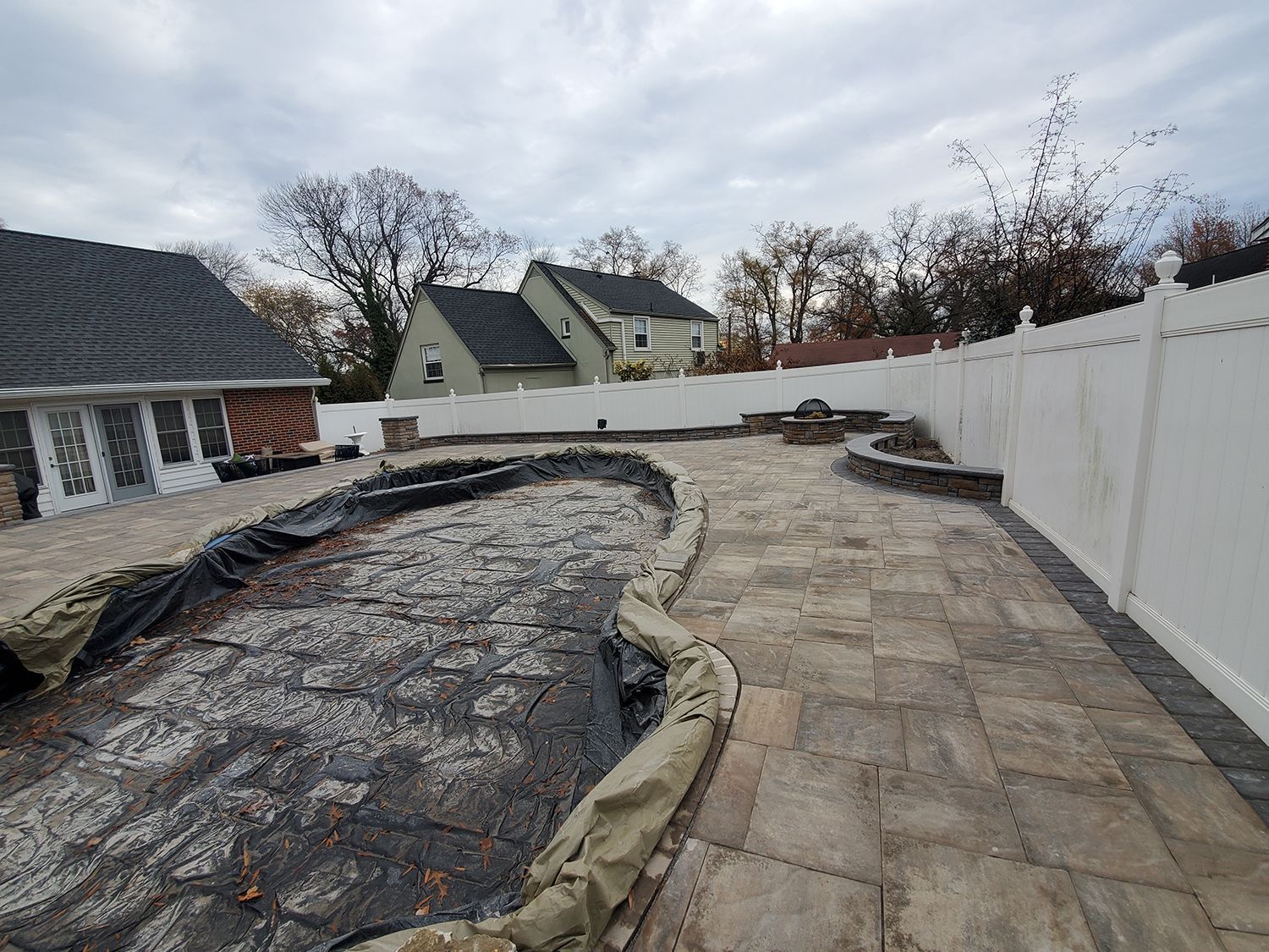 A patio with a white fence and a house in the background.