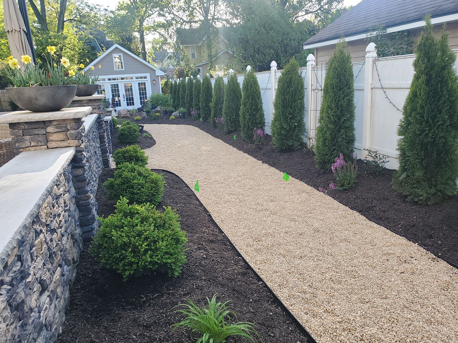 A gravel path leading to a house with a white fence.