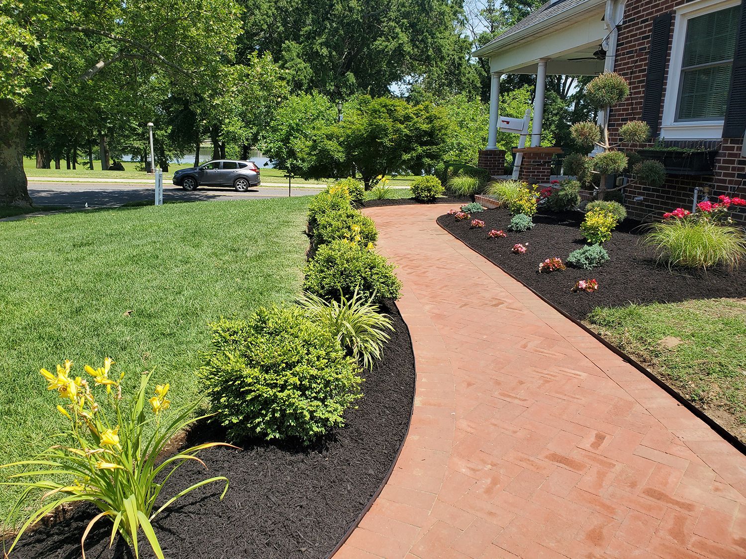 A walkway leading to a house with a car parked in the driveway.