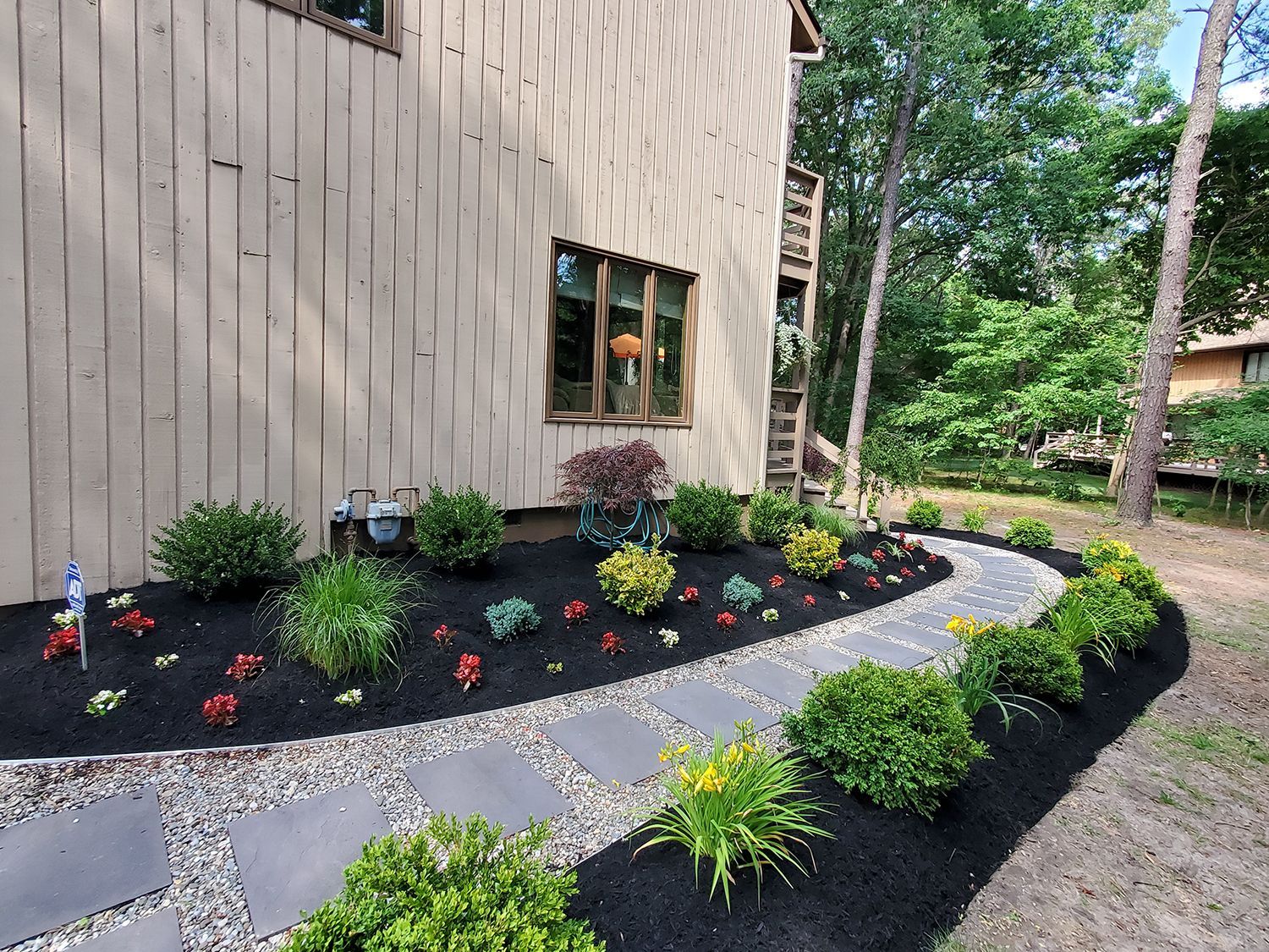 A walkway leading to a house surrounded by flowers and shrubs
